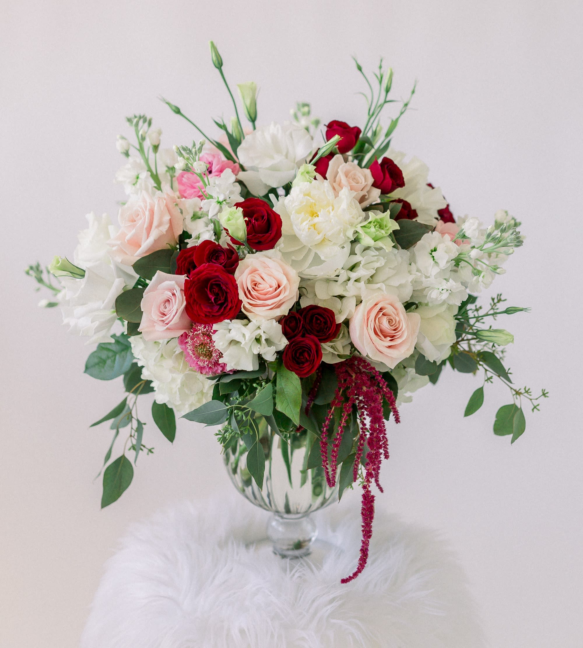 Bouquet of red, blush, and white flowers in a clear glass vase