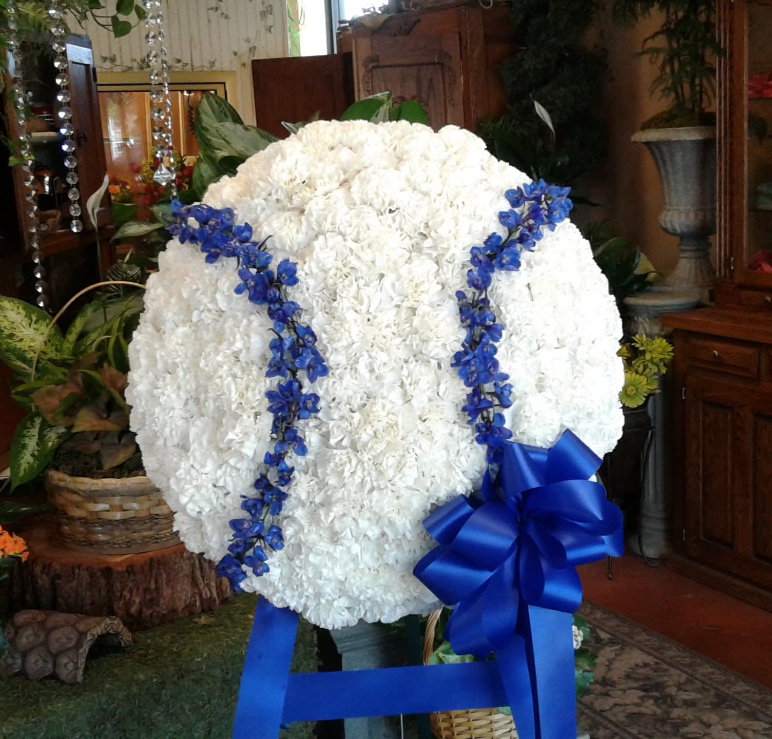 Large white floral standing spray with blue ribbon and blue accents