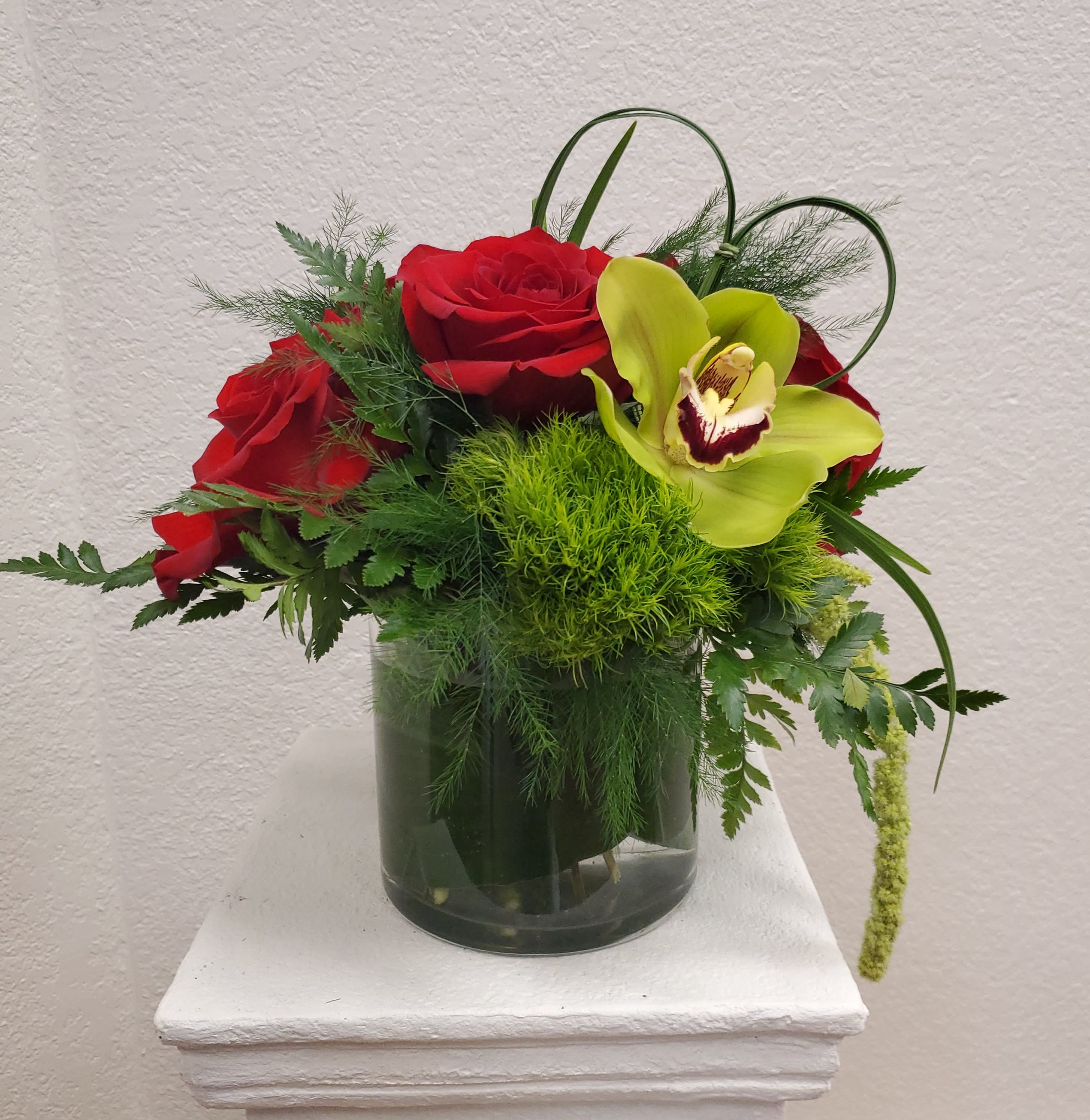 Red roses and a green orchid in a glass vase