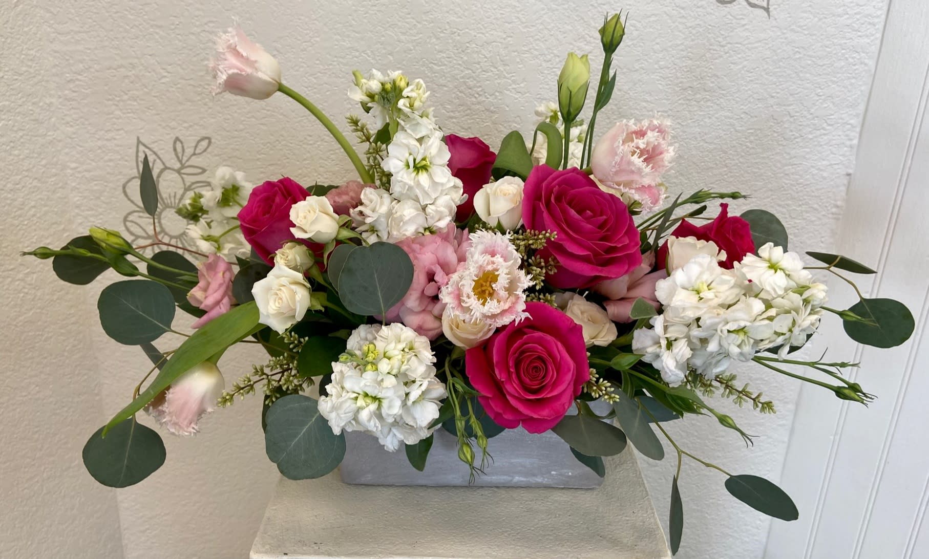 Pink and white rose arrangement in a gray rectangular vase