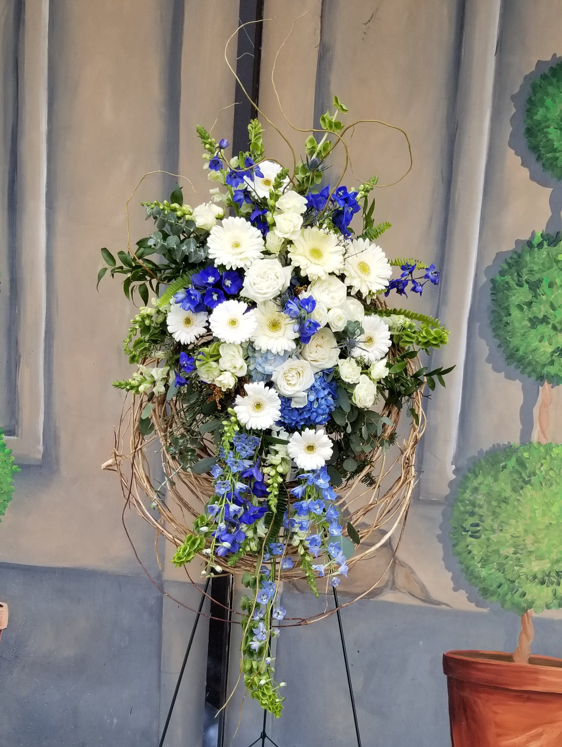 Tall floral spray with white and blue flowers in a twig frame