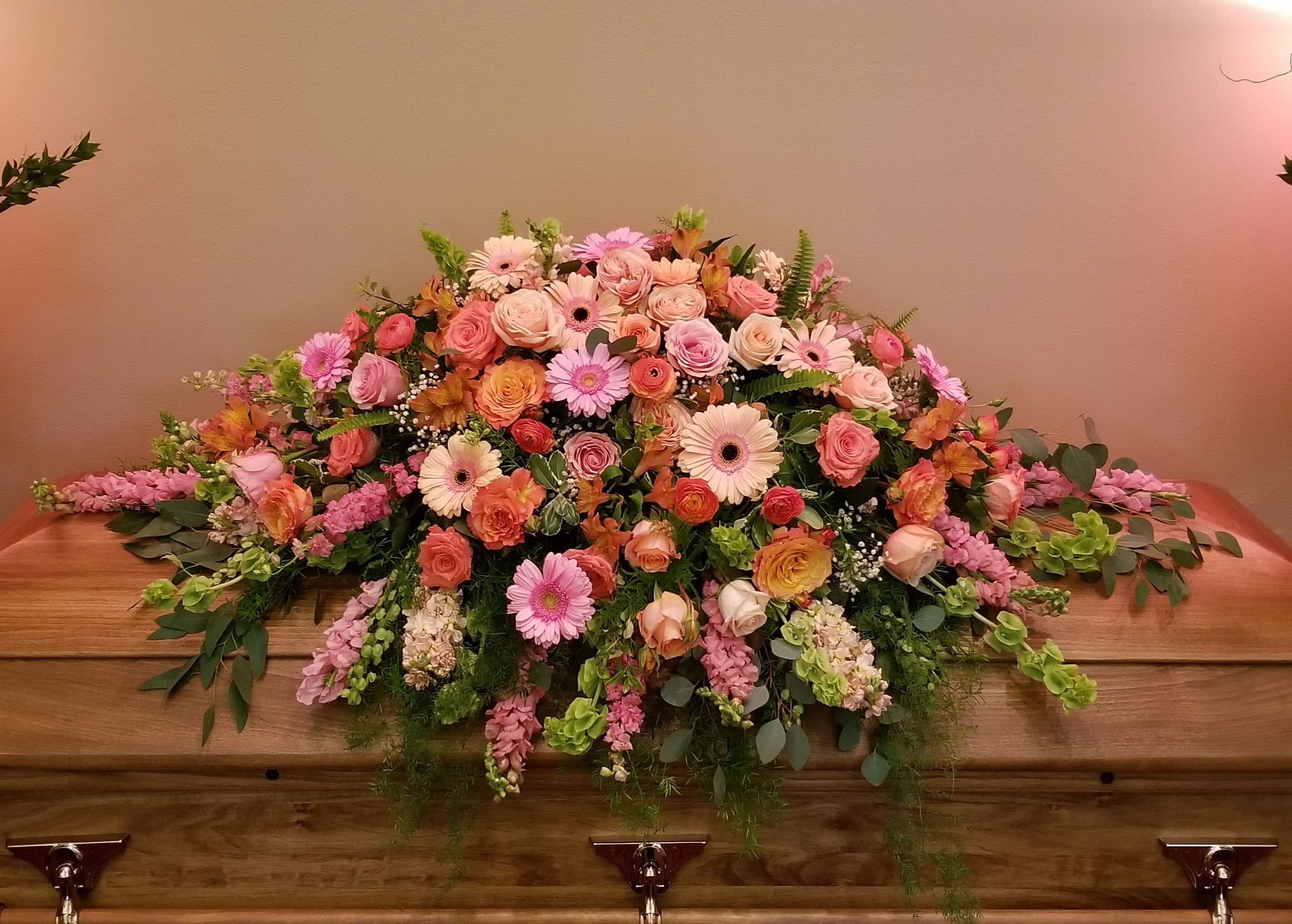 Large pink and peach floral casket spray with roses and daisies