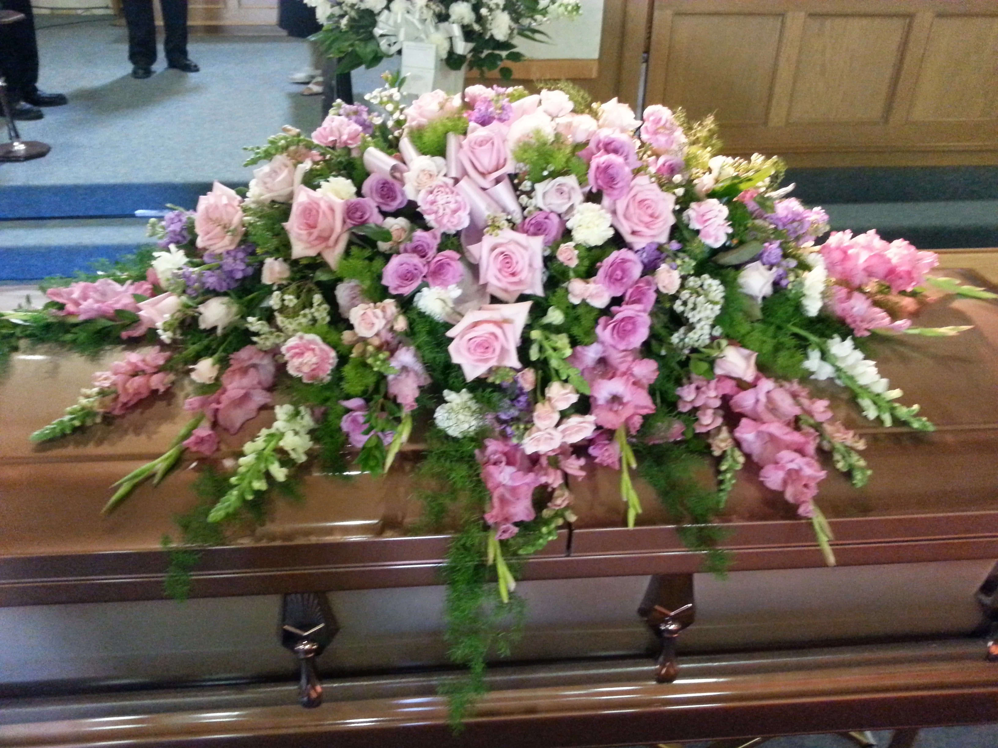 Large pink and white floral casket spray on a coffin