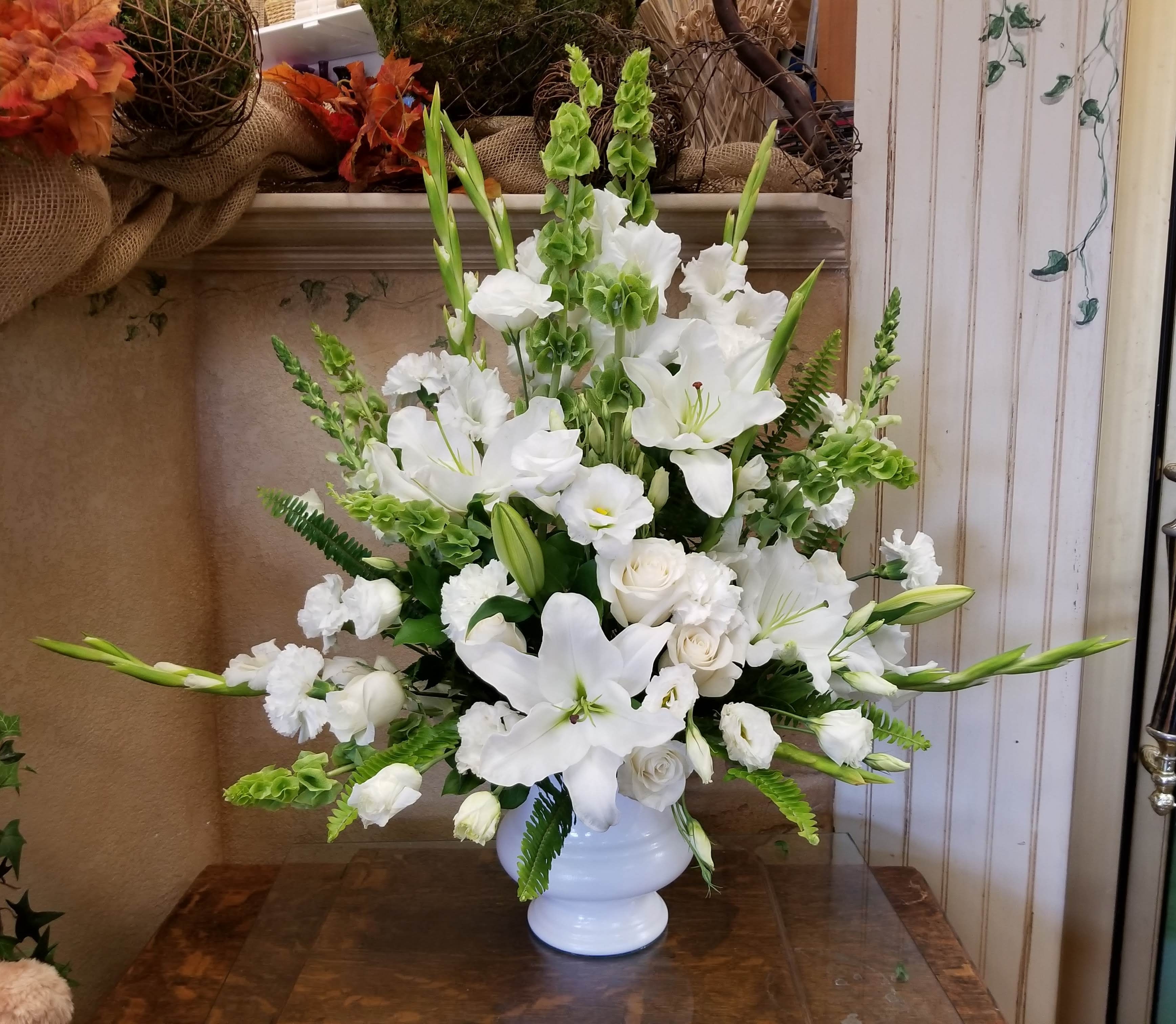 White lilies and roses arranged in a white vase