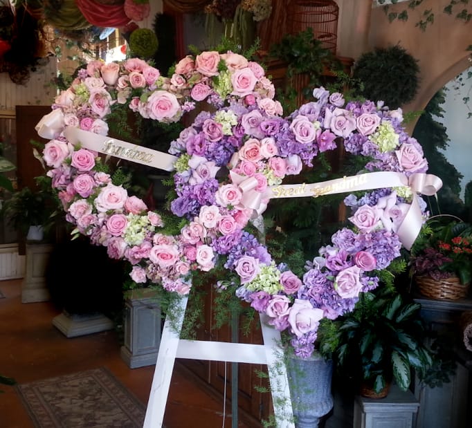 Two heart-shaped floral wreaths of pink and lavender roses on easels