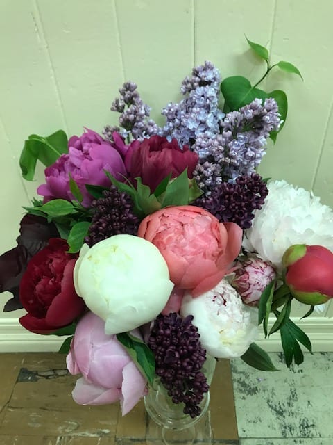Bouquet of peonies and lilacs in a clear glass vase