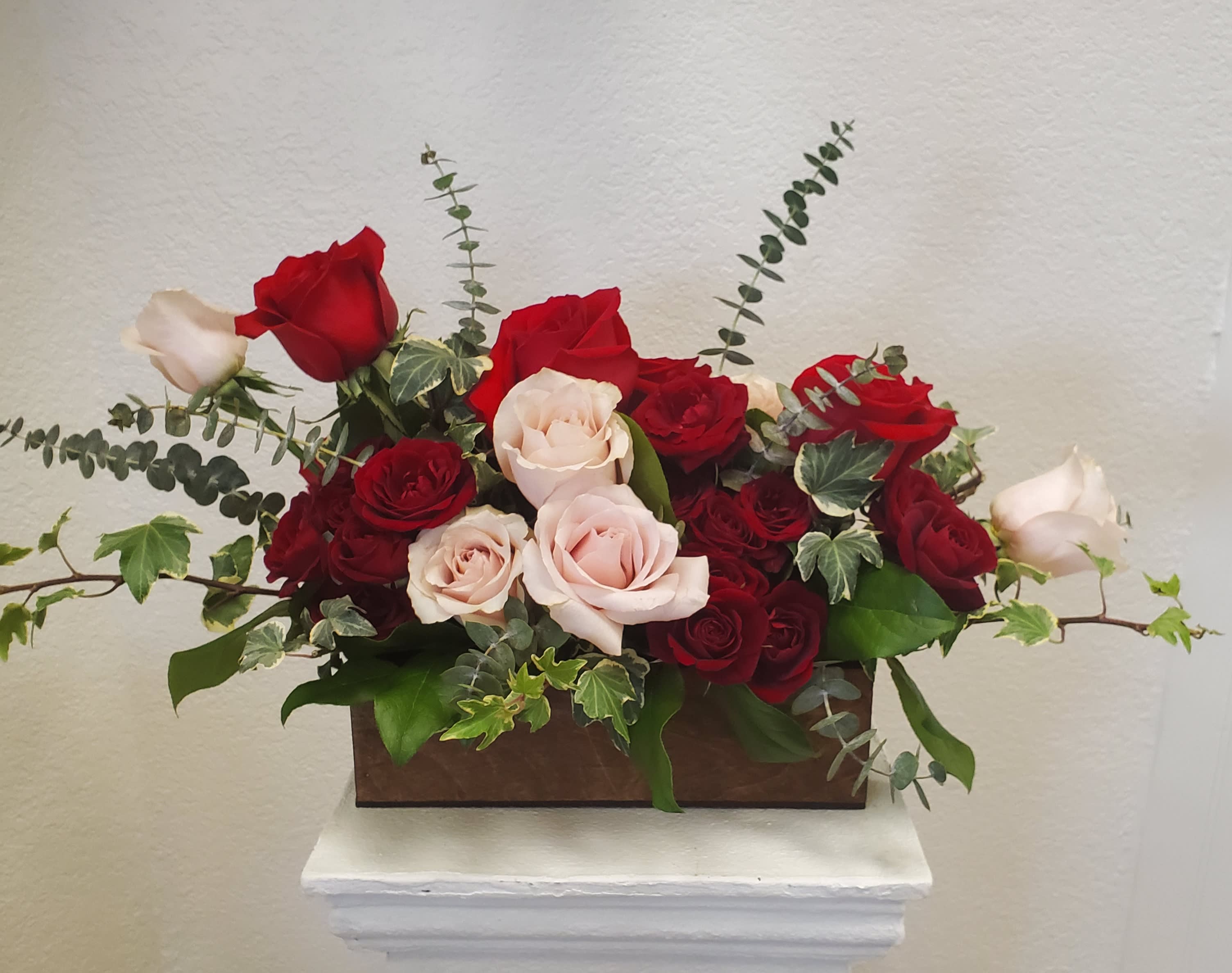 Red and blush roses arranged in a rectangular wooden box