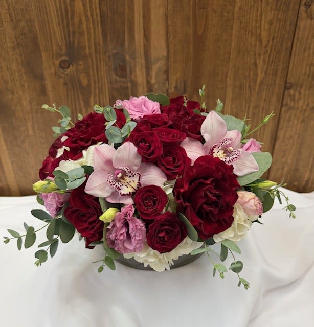 Bouquet of red roses and pink orchids in a low vase