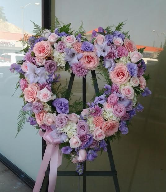 Heart-shaped floral wreath with pink and lavender roses on an easel