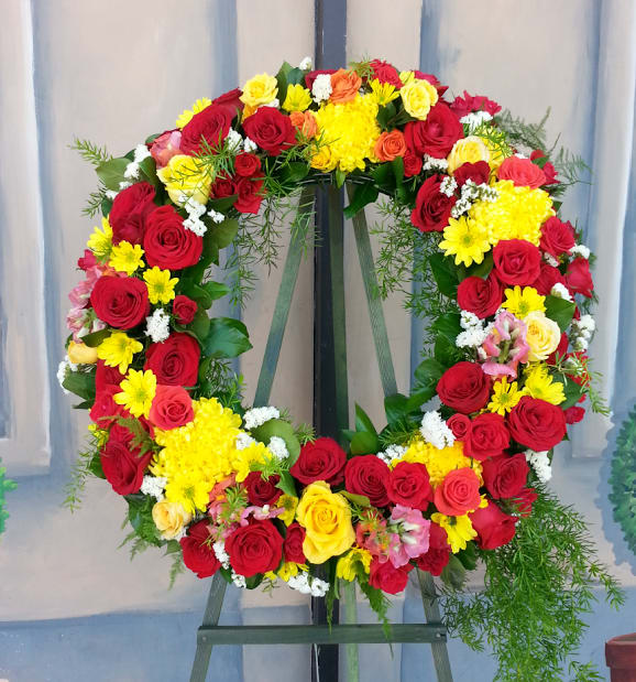 Large floral wreath of red, yellow, and pink roses on an easel