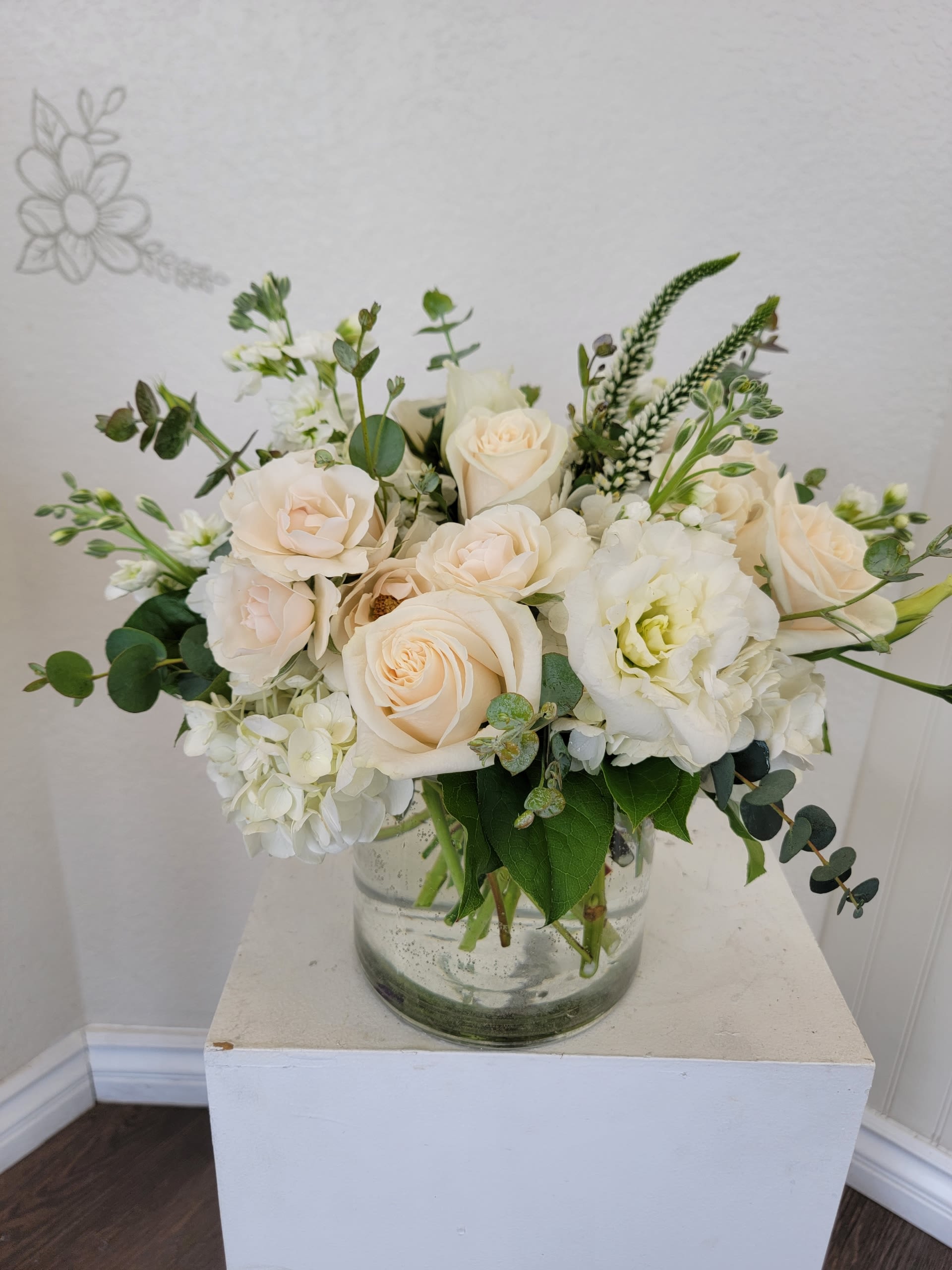 Cream roses and white blooms arranged in a clear glass vase