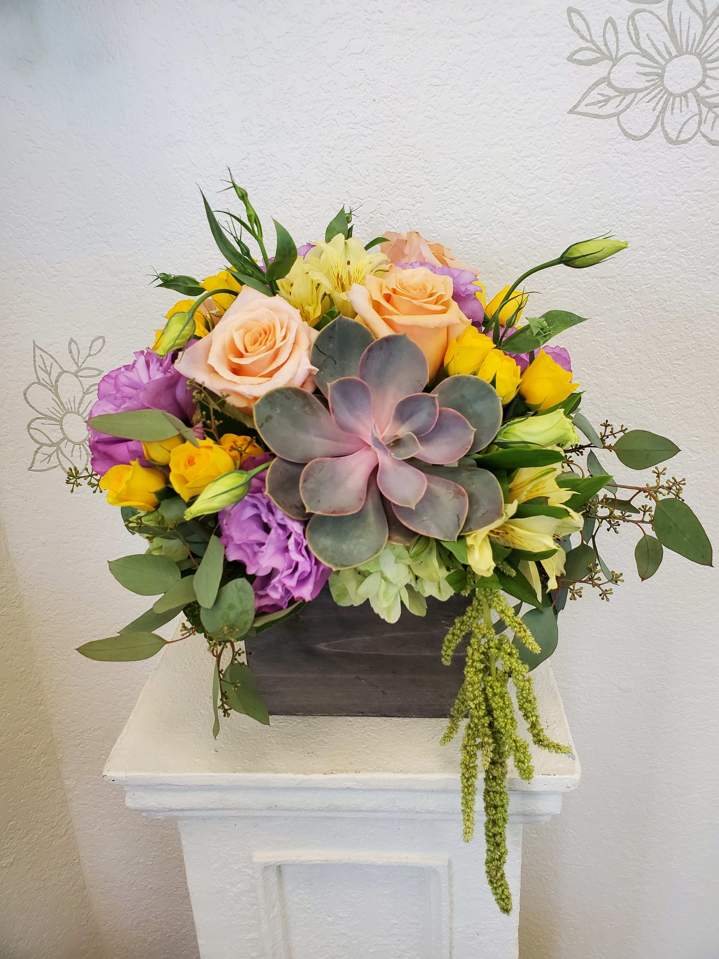 Mixed bouquet with roses, lisianthus, and a succulent in a dark box