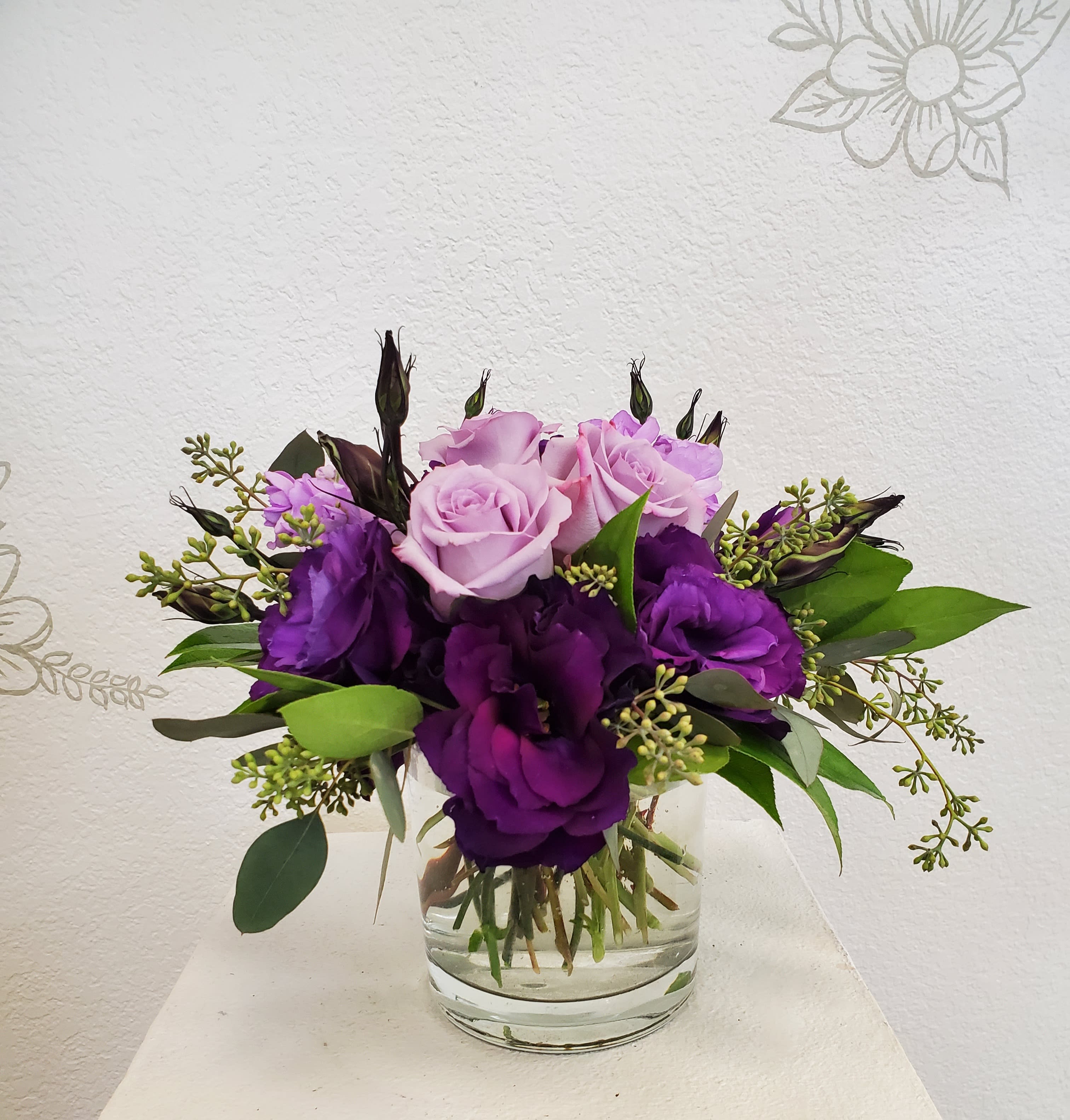 Purple and pink rose bouquet in a clear glass vase