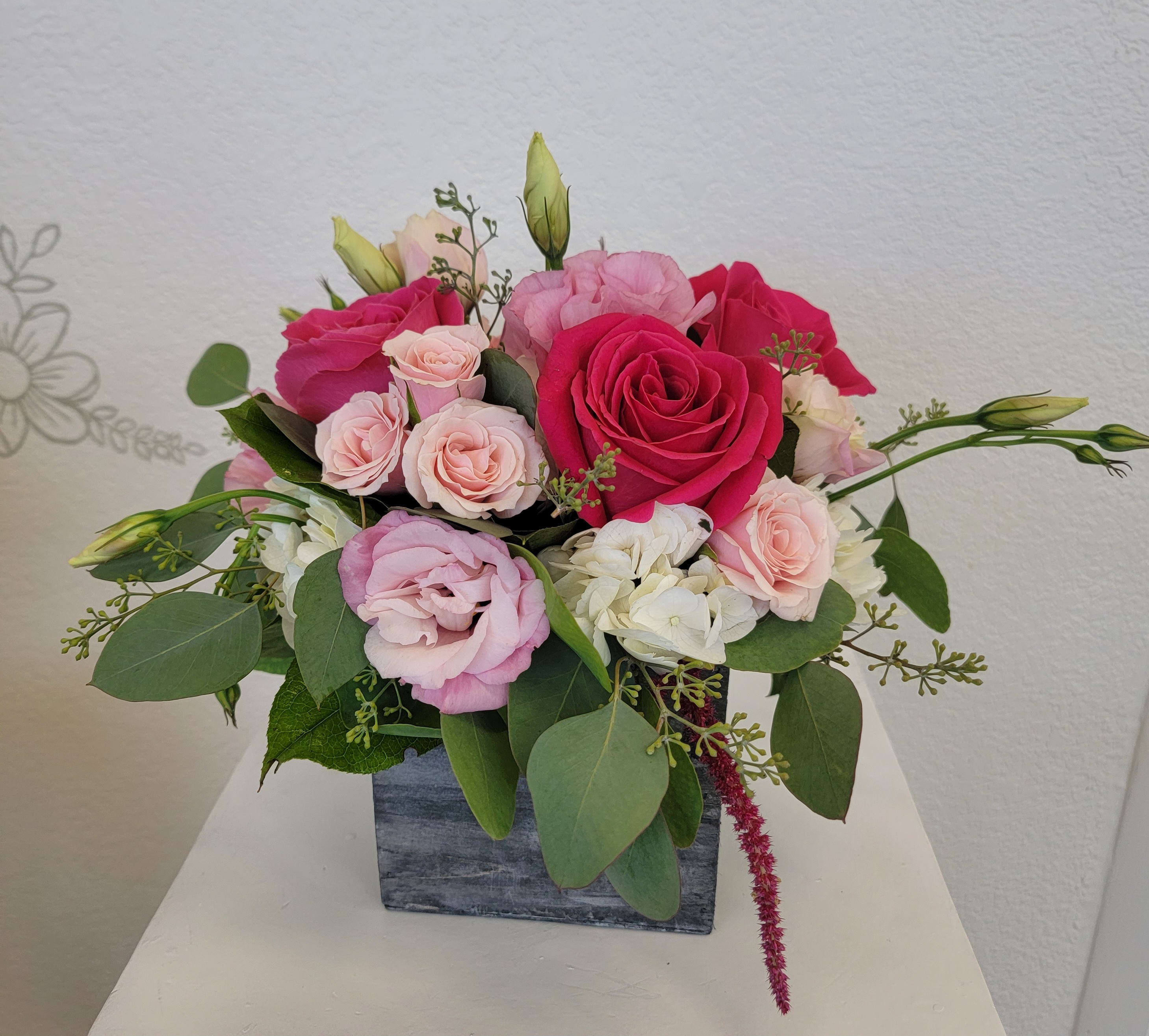 Pink and white rose arrangement in a square gray vase