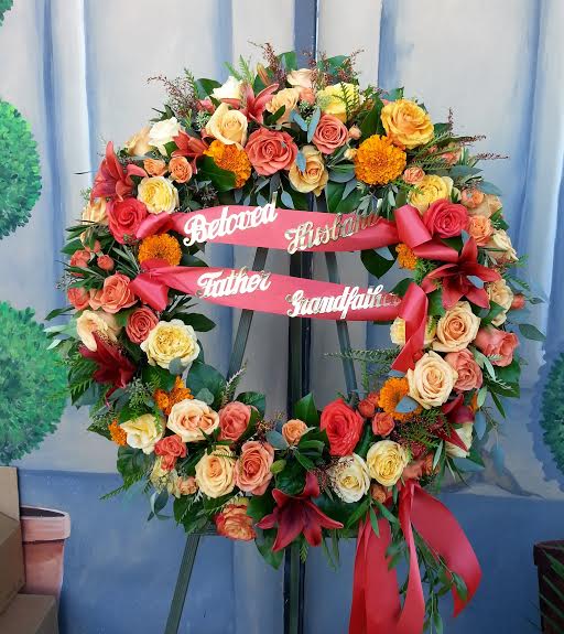 Large floral funeral wreath with roses and ribbons on an easel