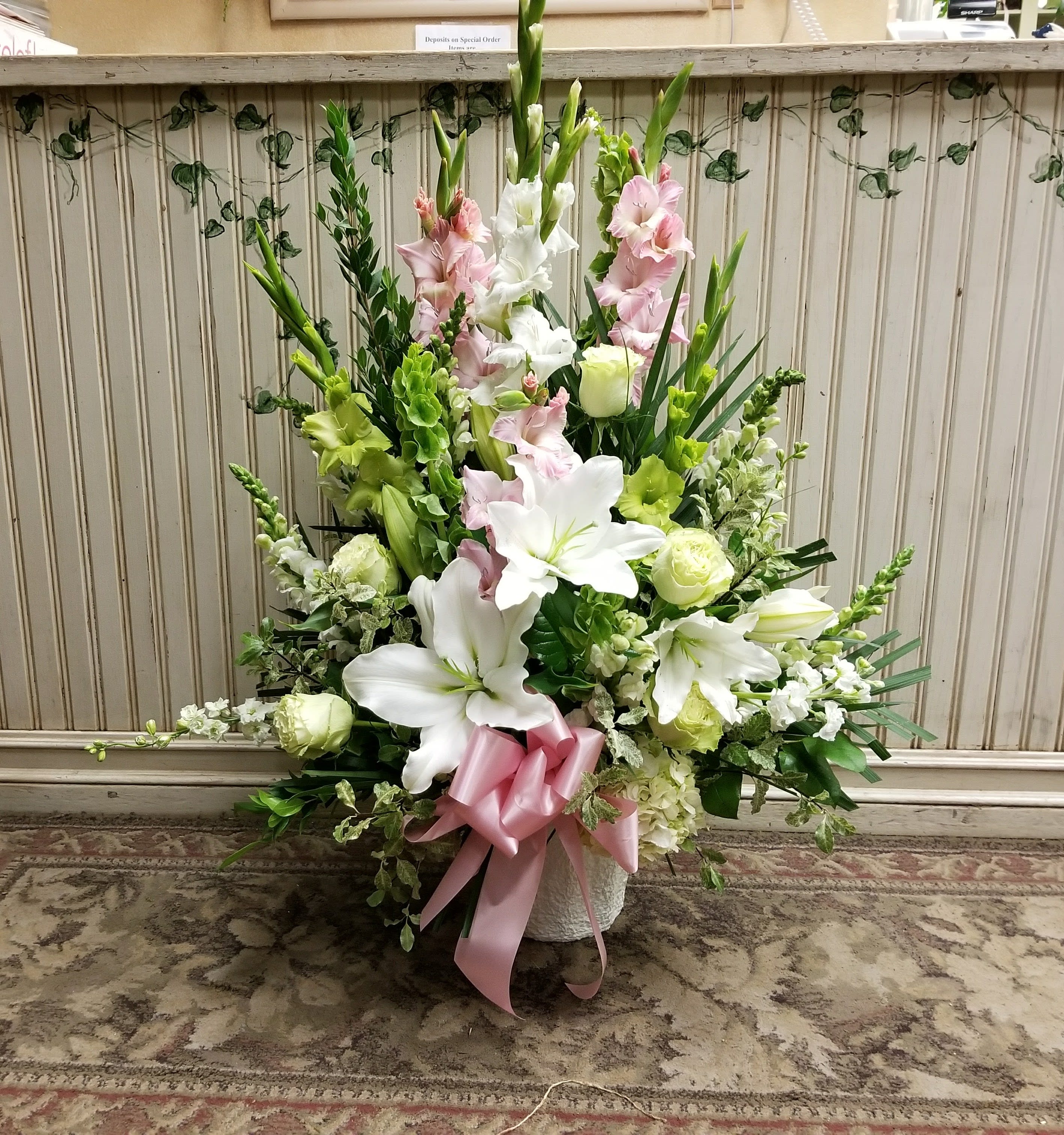Tall floral arrangement with white lilies and pink gladiolus in a vase