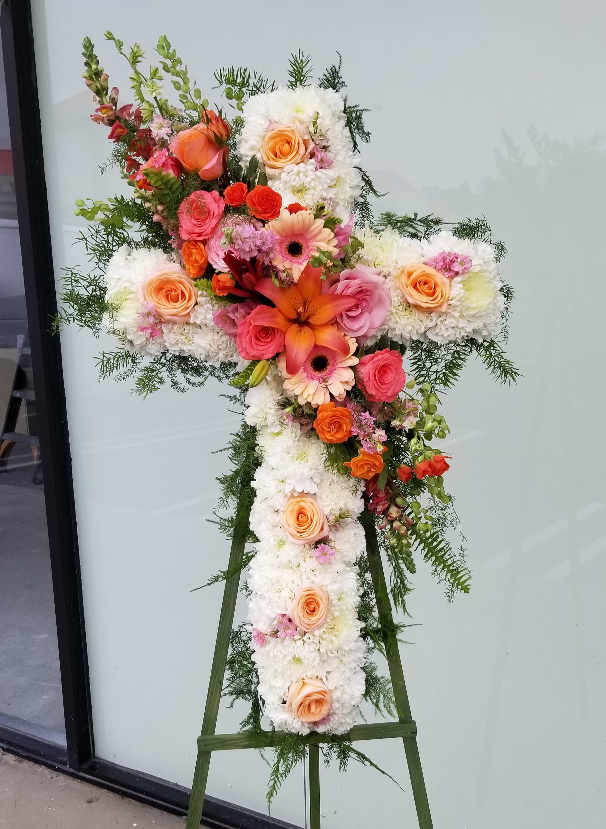 Cross-shaped floral standing spray with white blooms and peach, pink, and orange flowers