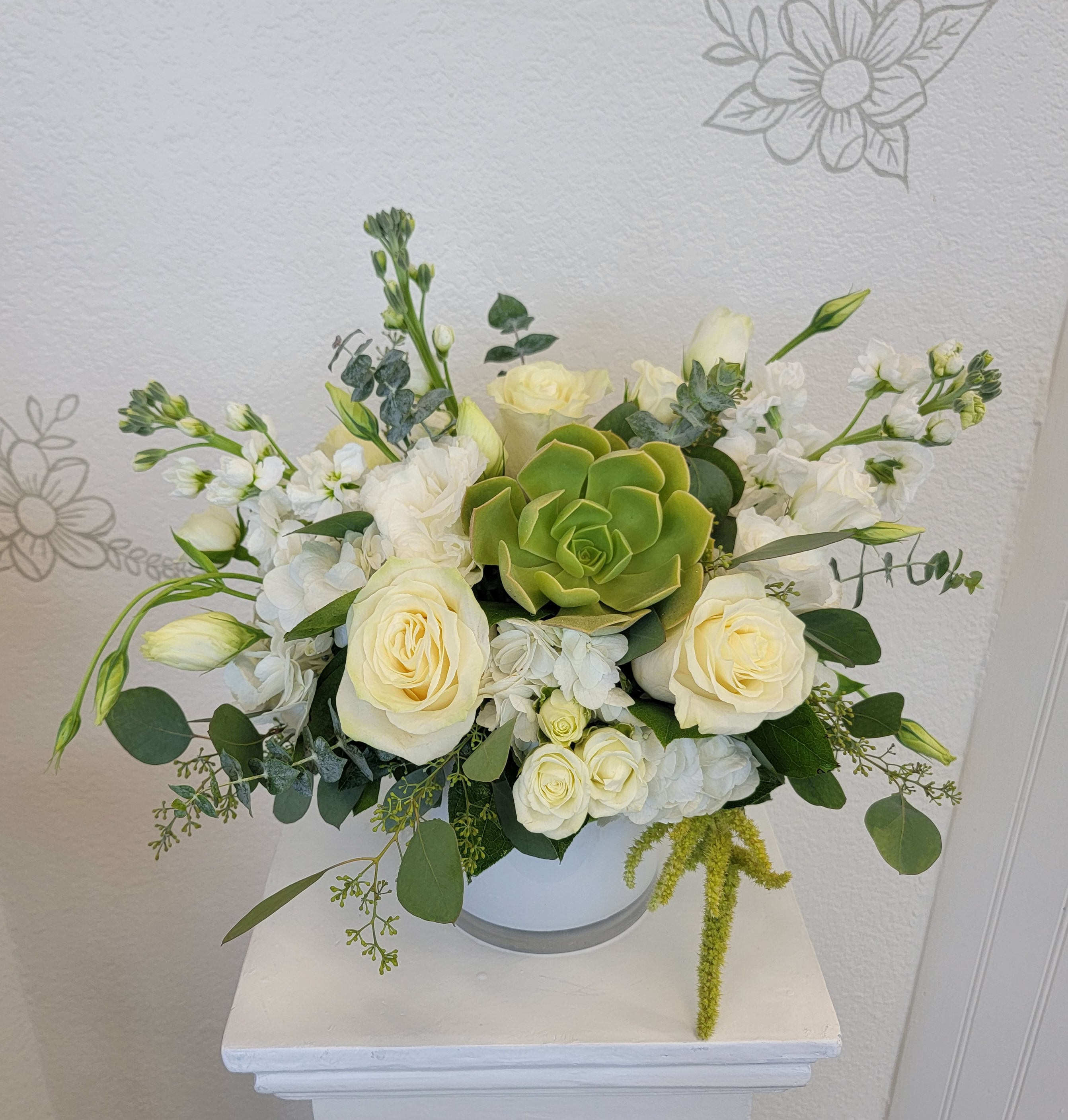 White rose arrangement with a green succulent in a white vase