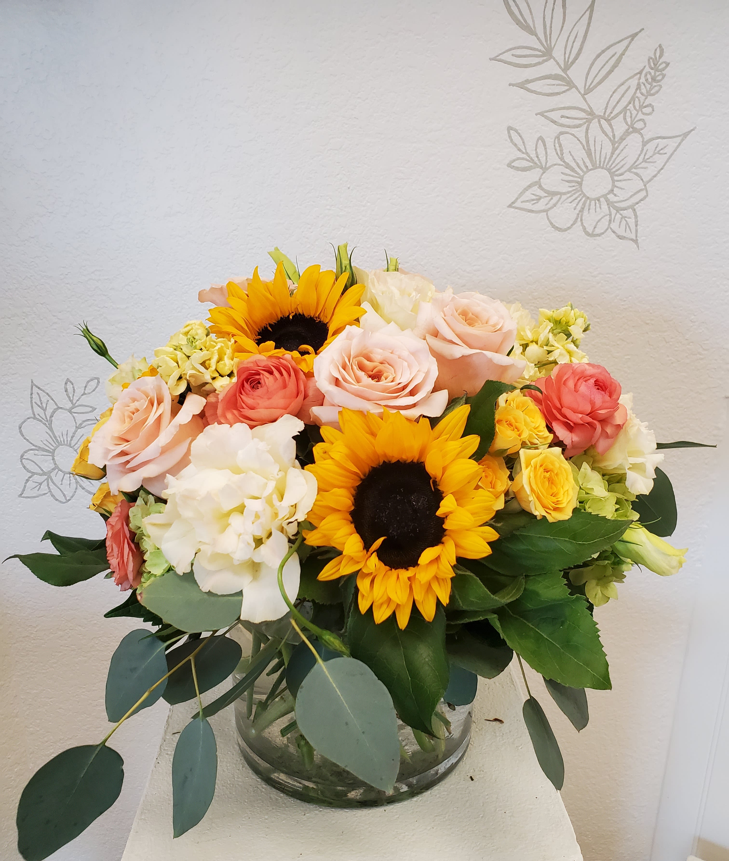 Bouquet of sunflowers, roses, and hydrangeas in a glass vase