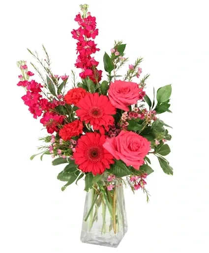 Pink and red mixed flower arrangement in a clear glass vase