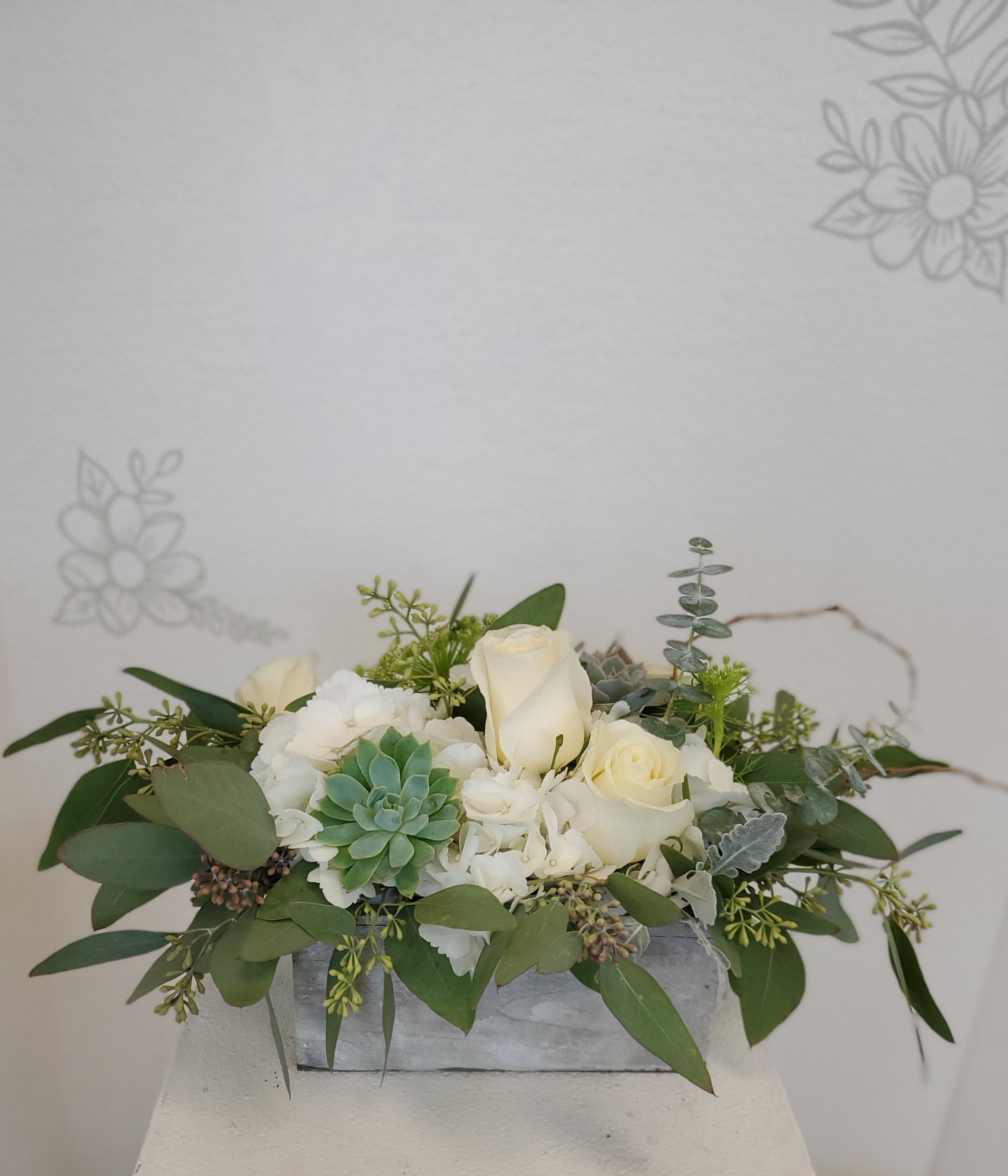 White roses and succulents arranged in a low rectangular container