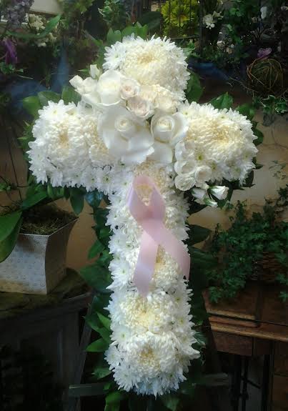 White floral cross arrangement with a pink ribbon