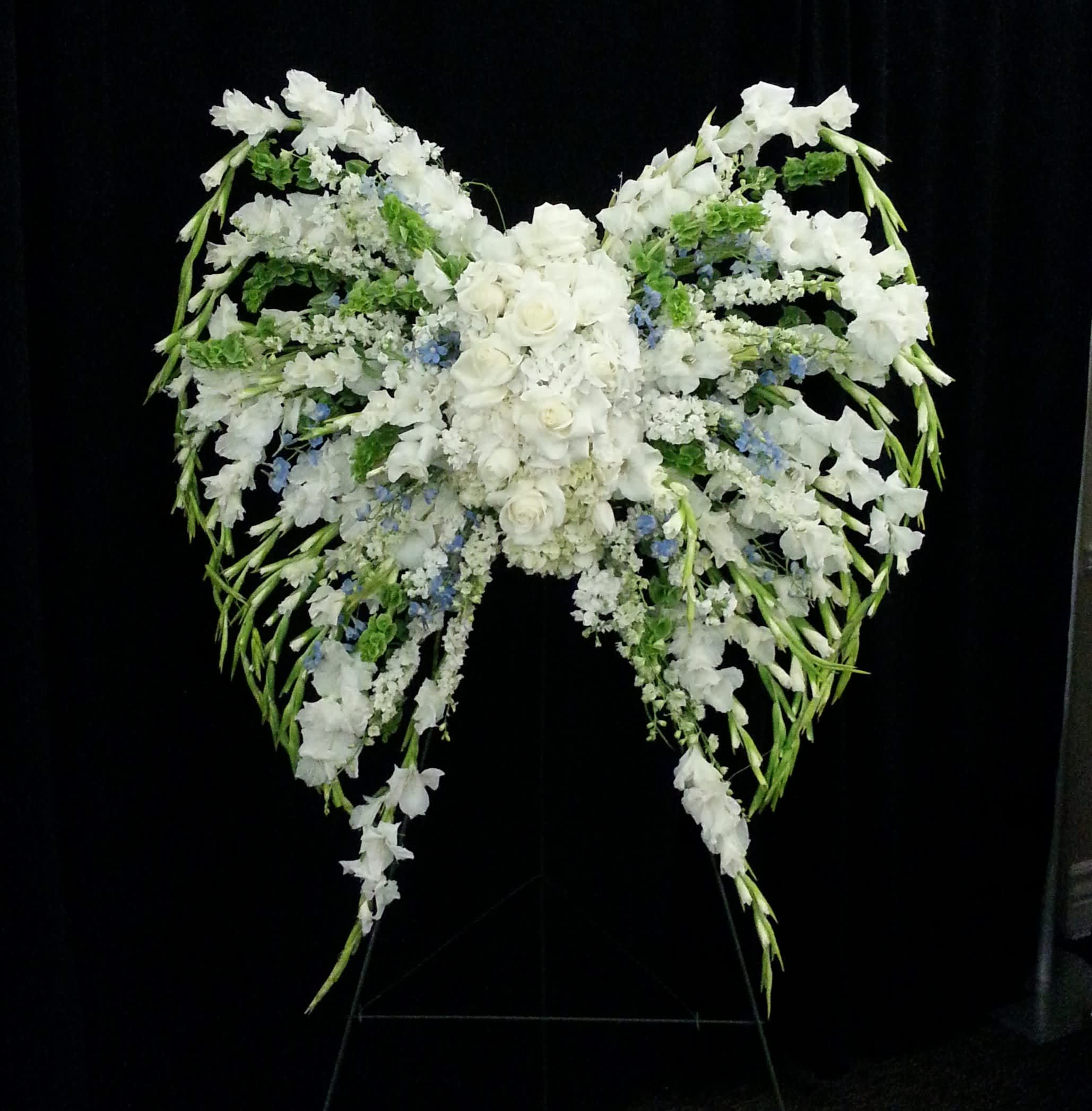 Large white floral spray arranged in a winged shape on a stand