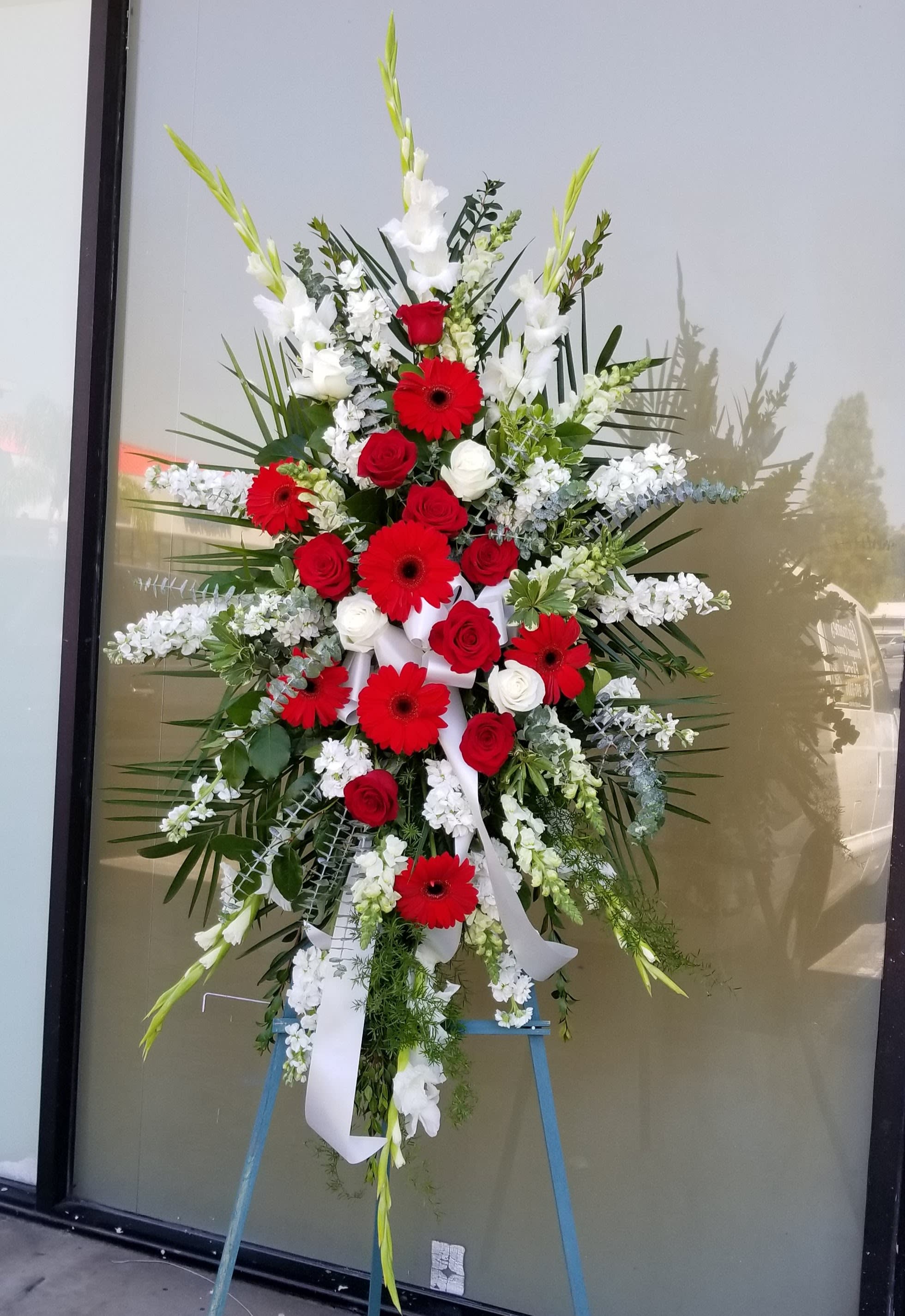 Large standing floral spray with red and white flowers on an easel