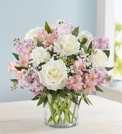 White roses and pink flowers arranged in a clear glass vase
