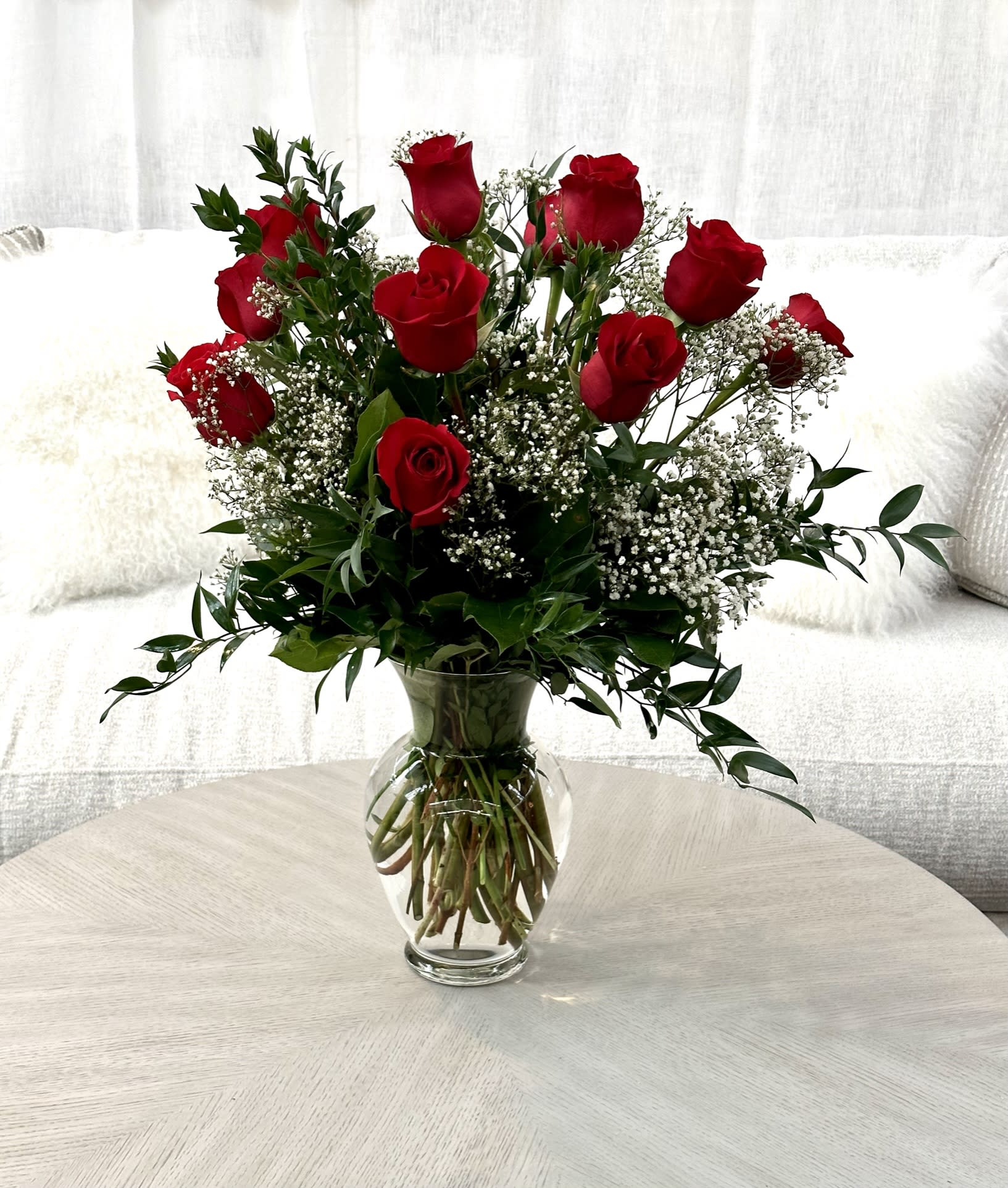 Red roses arranged in a clear glass vase with baby's breath