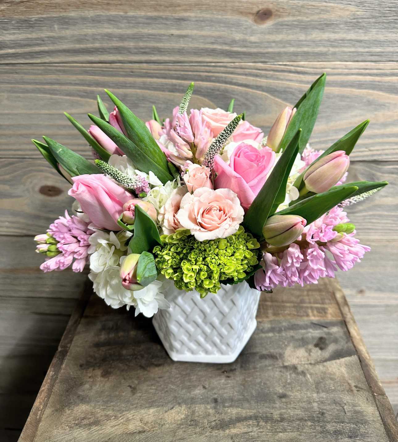 Pink and white floral arrangement in a white woven vase