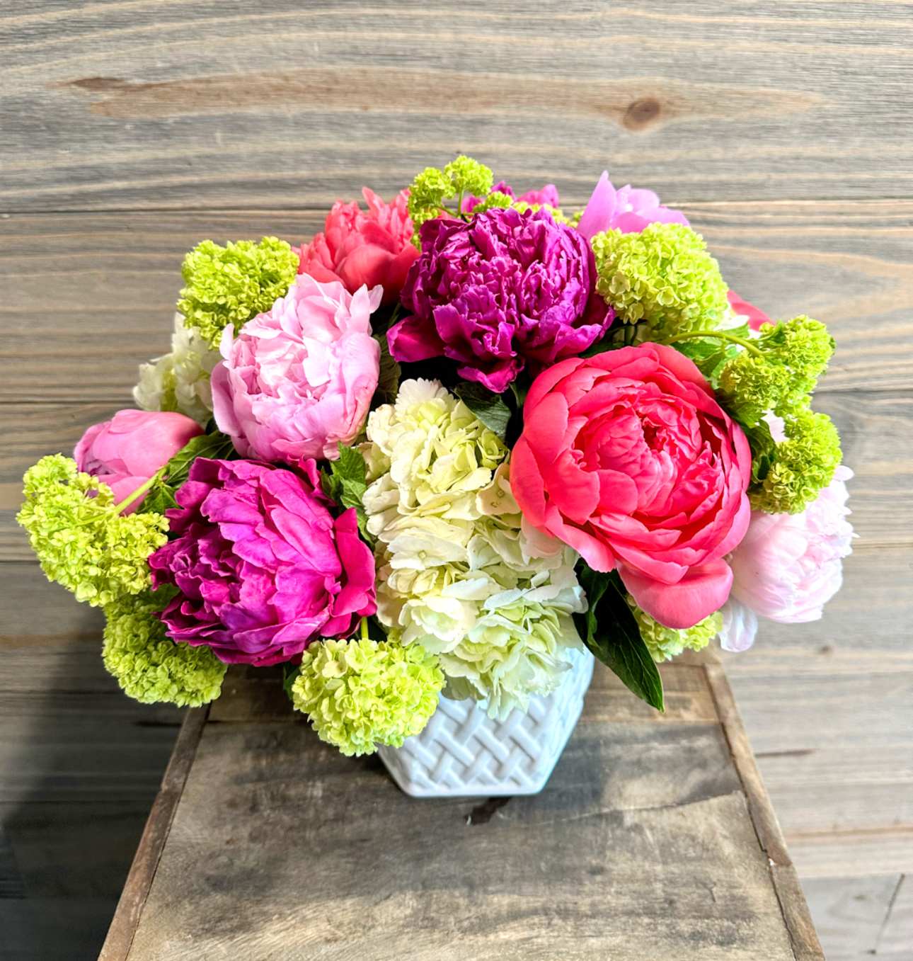 Pink and magenta flowers arranged in a white vase