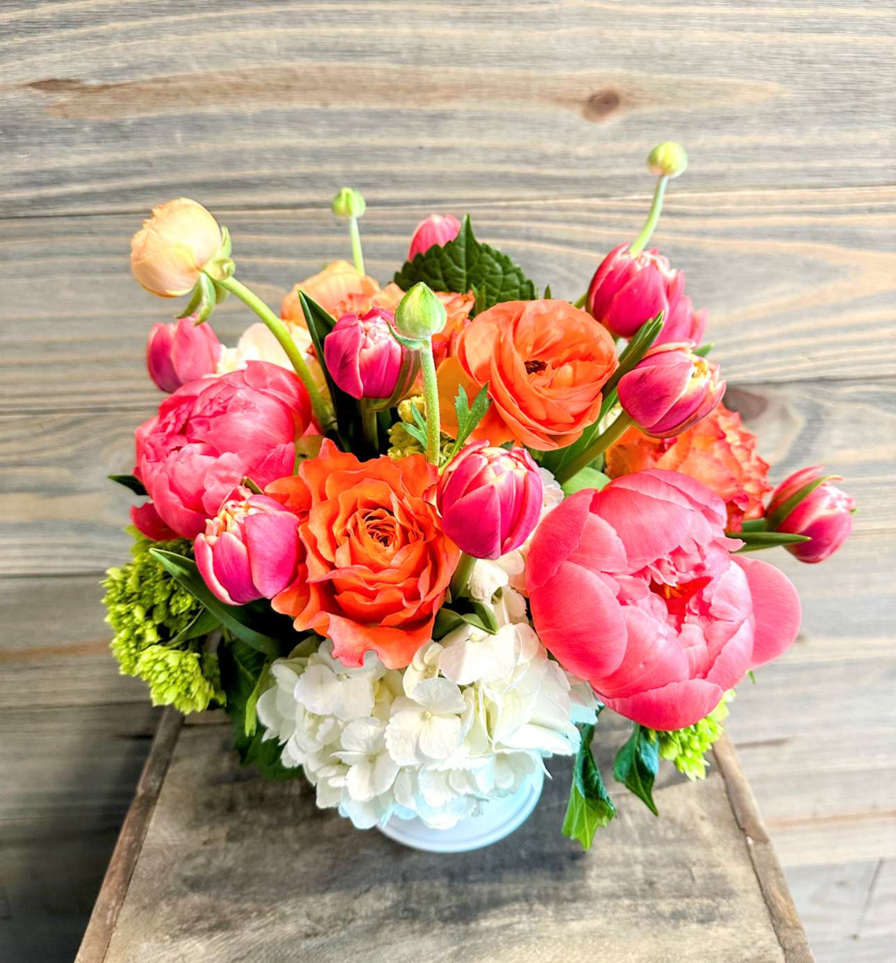 Shimmer - A mix of coral, peach and orange tones of bright spring blooms in a beautiful white container.