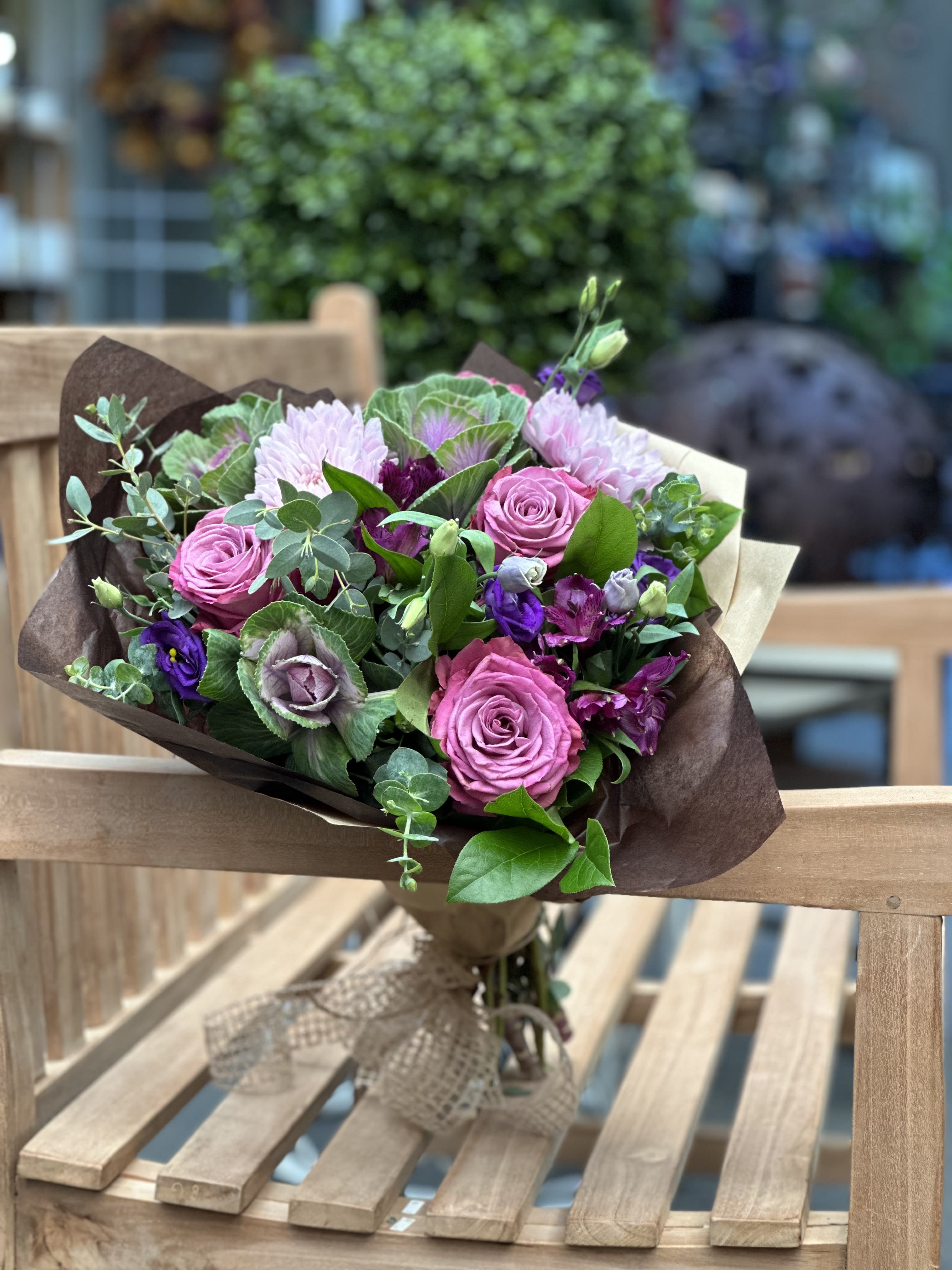 Bouquet of pink roses and purple flowers wrapped in brown paper
