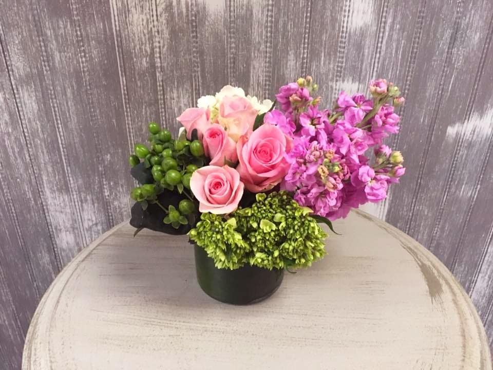 Pink roses and purple flowers arranged in a black container