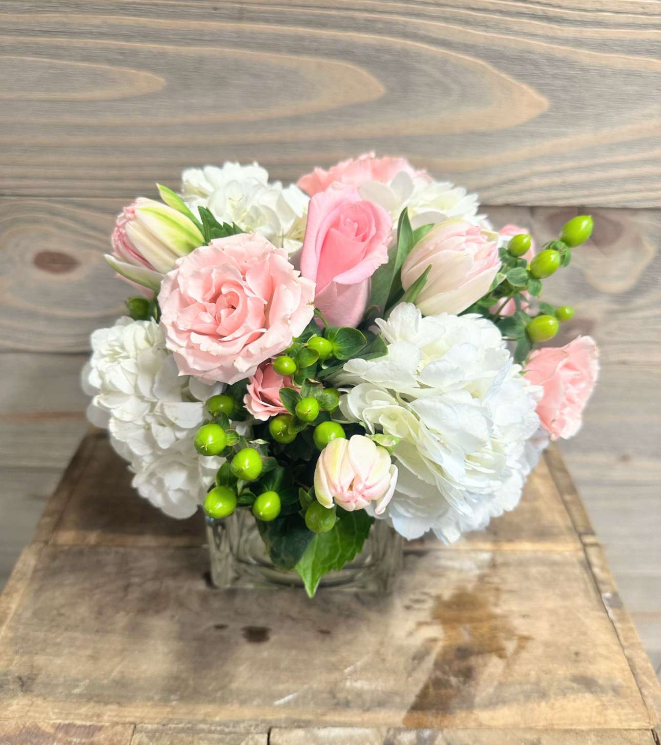 Love Song - A beautiful floral arrangement with all shades of pale pink flowers and soft white blooms in a small compact style vase.
