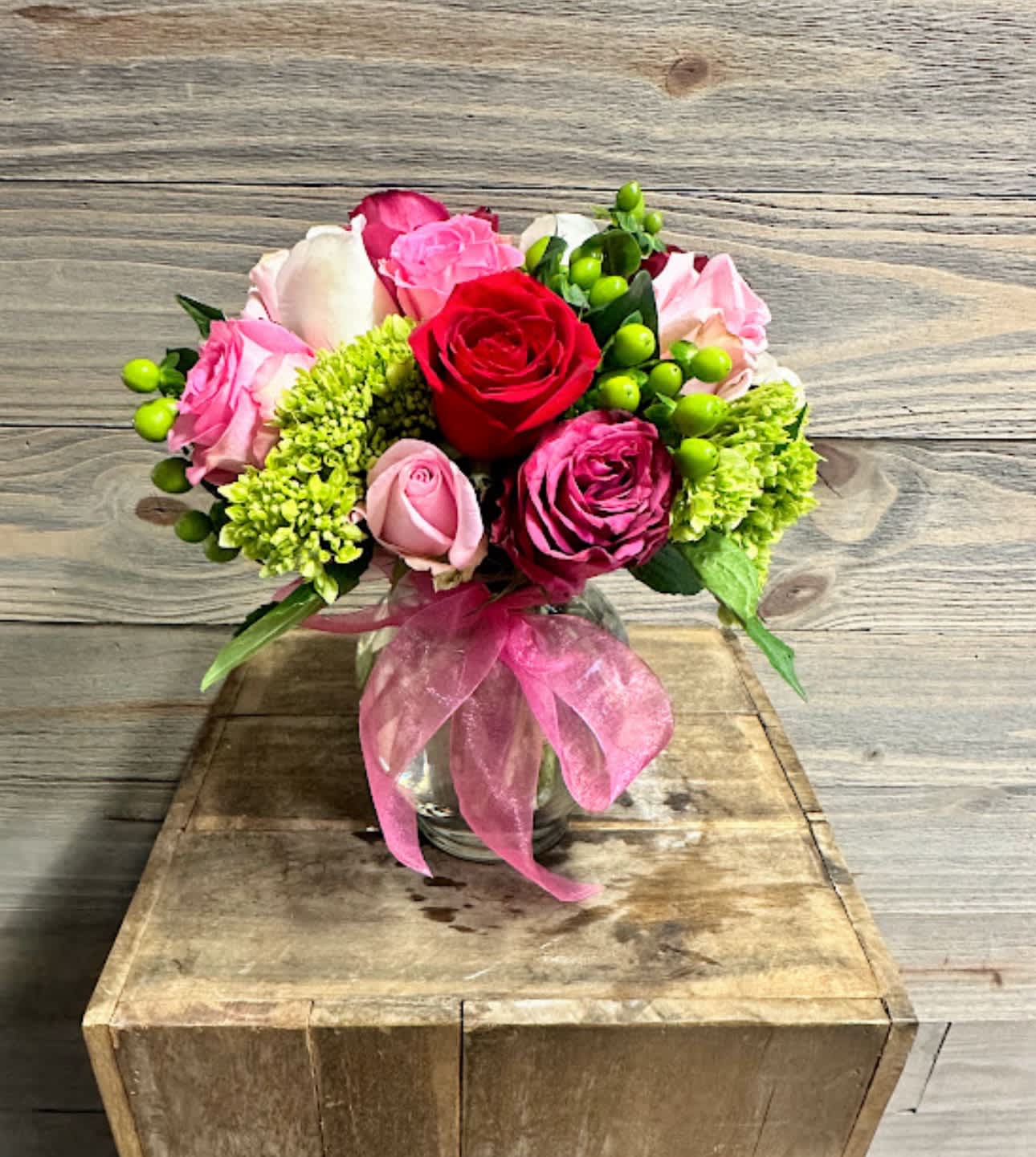 Love Struck - This beautiful vase is a compact style arrangement featuring 12 roses of different colors with hydrangeas and hypericum with a simple chiffon bow!