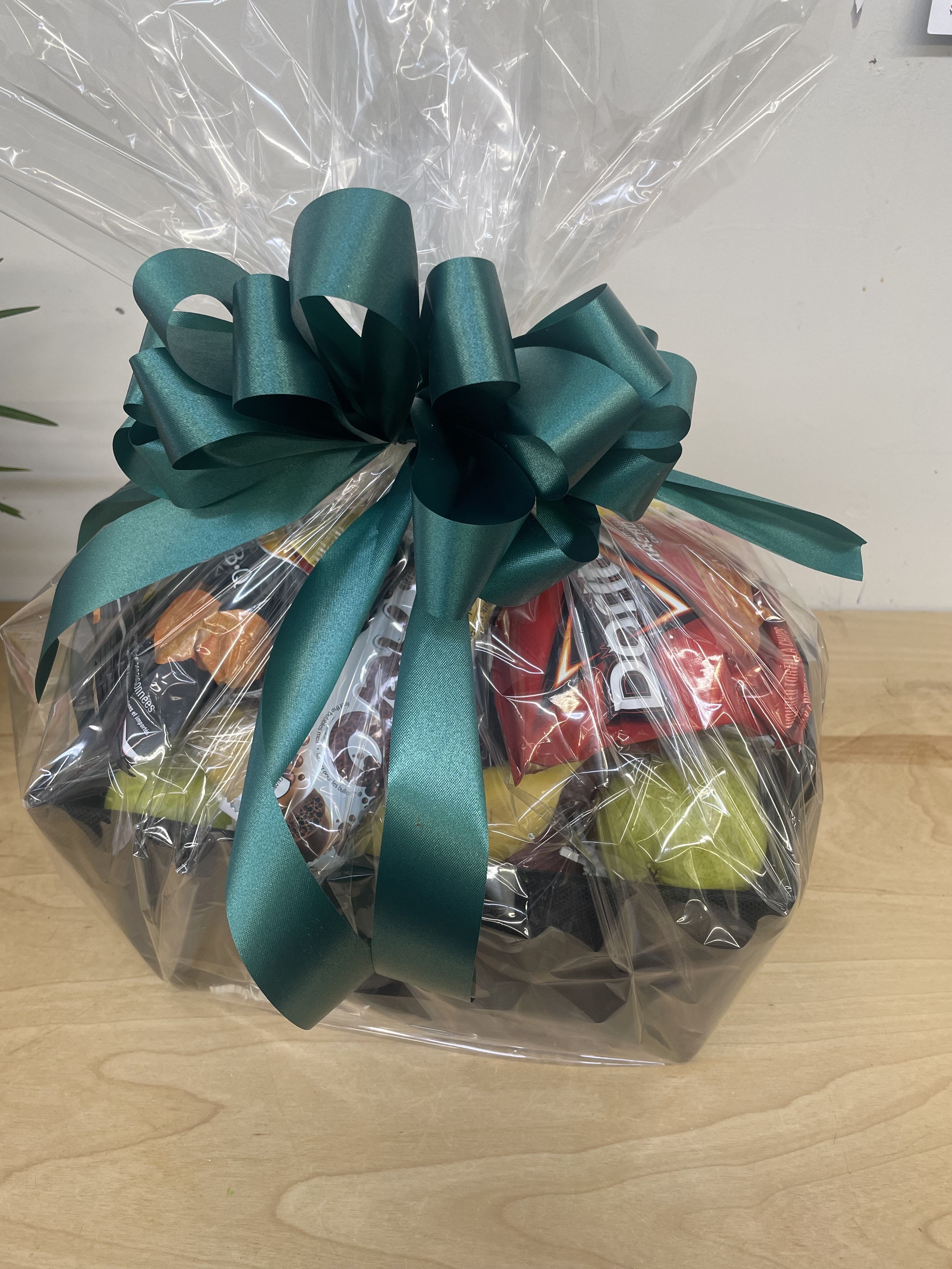 Gift basket wrapped in clear cellophane with a teal bow