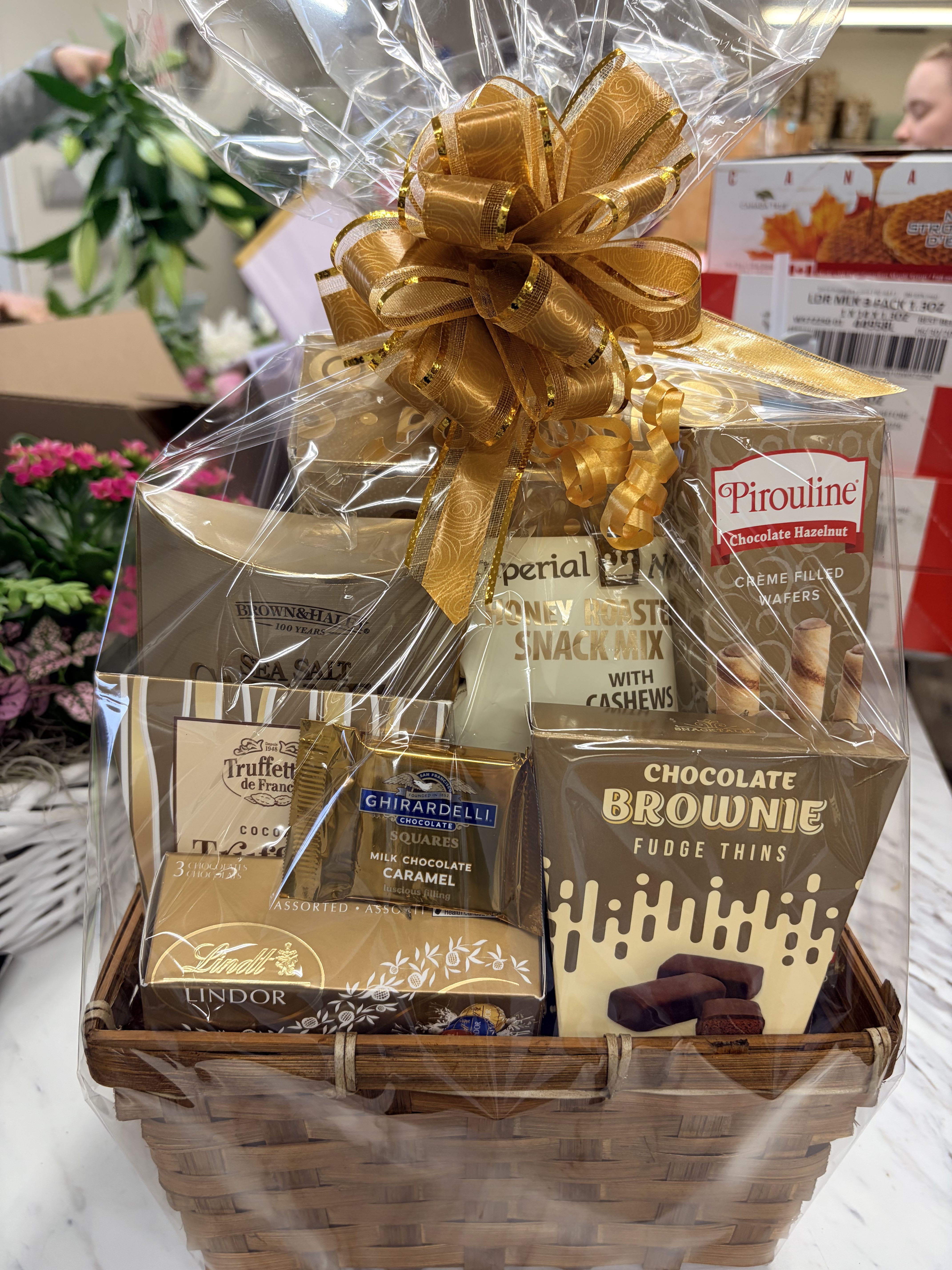 Gift basket of assorted chocolates and snack mixes wrapped with a gold bow