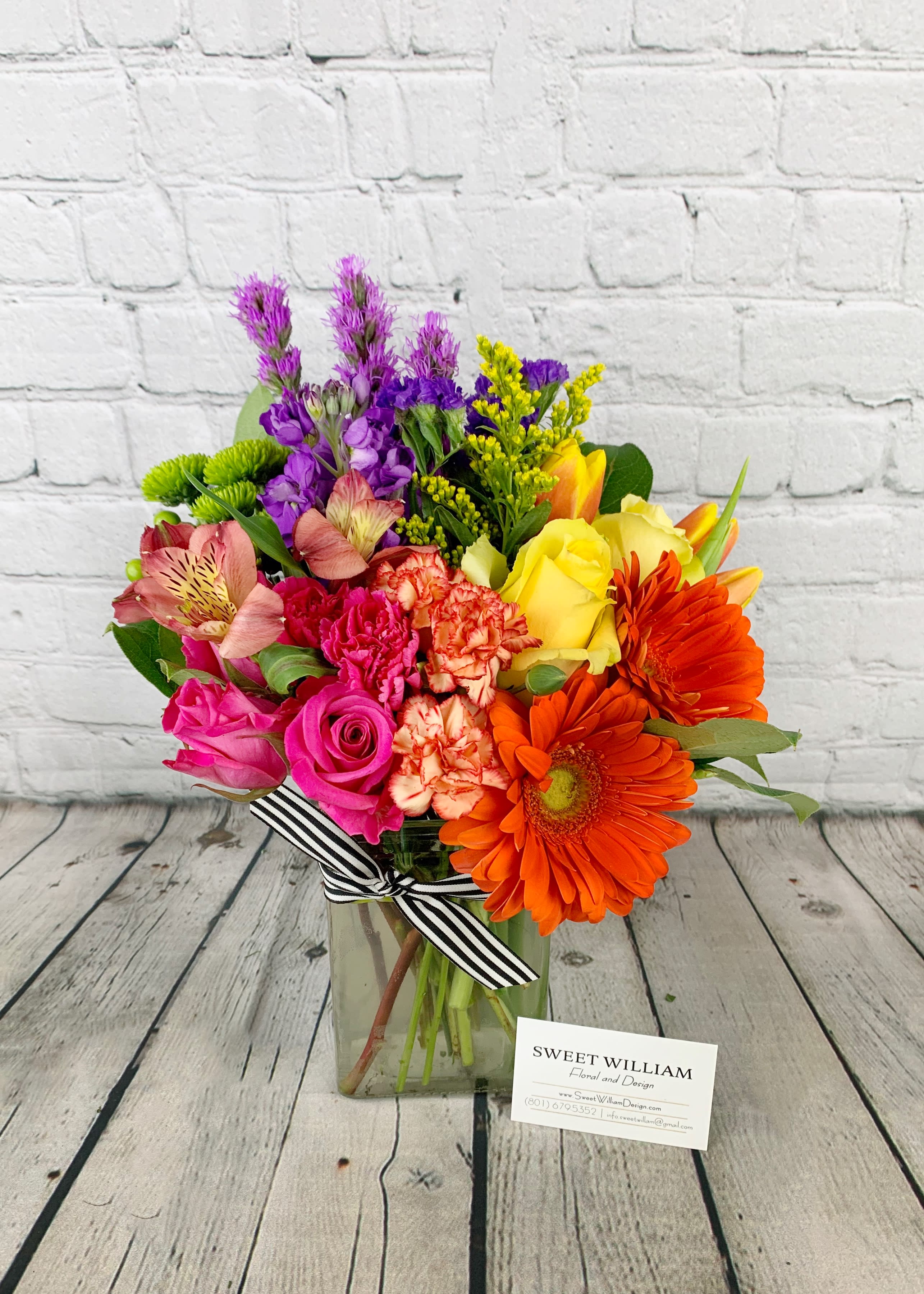 Colorful mixed bouquet in a glass vase with a striped ribbon