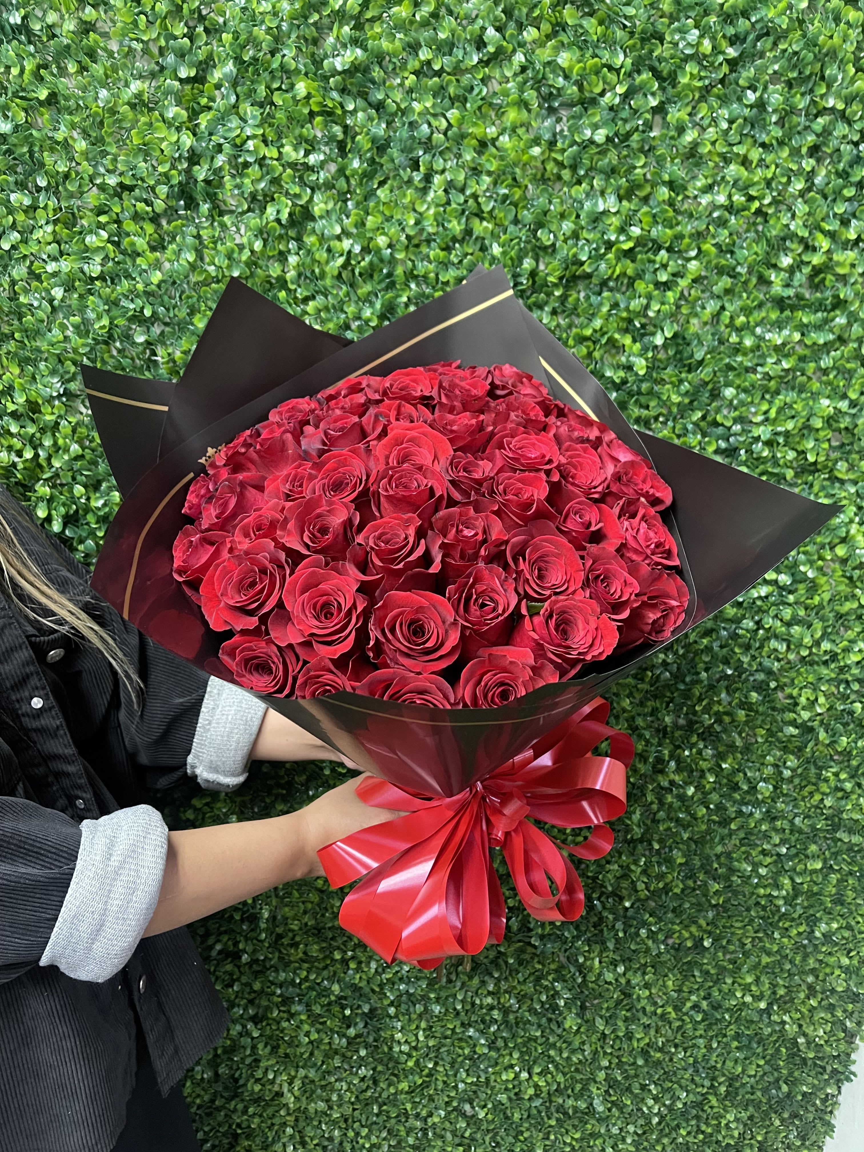 Large bouquet of red roses wrapped in black paper with a red ribbon