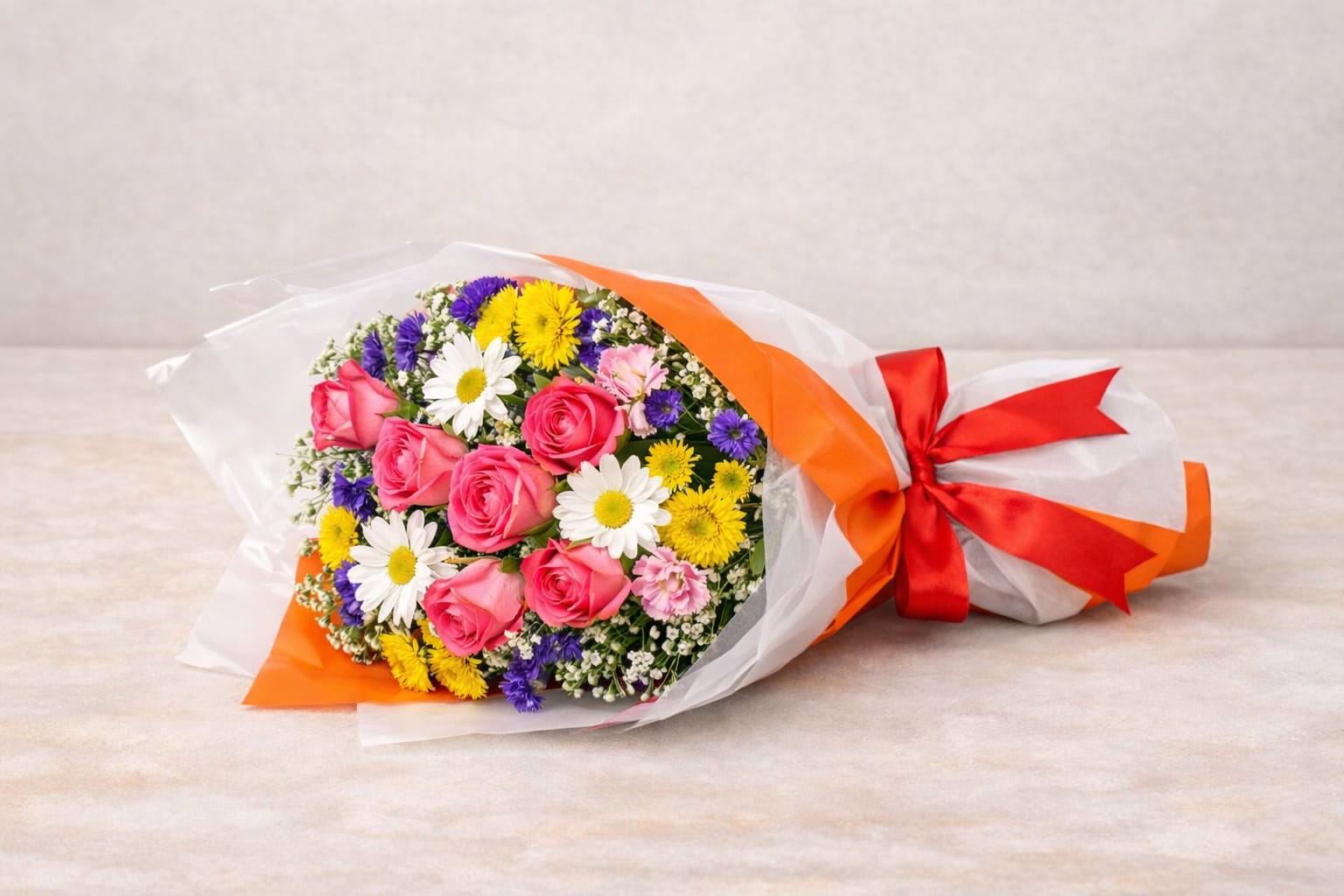 Success Blooms Wrap - A joyful mix of pink roses, daisies, mums, and statice wrapped in white paper with a satin bow — a vibrant way to celebrate achievement and new beginnings.