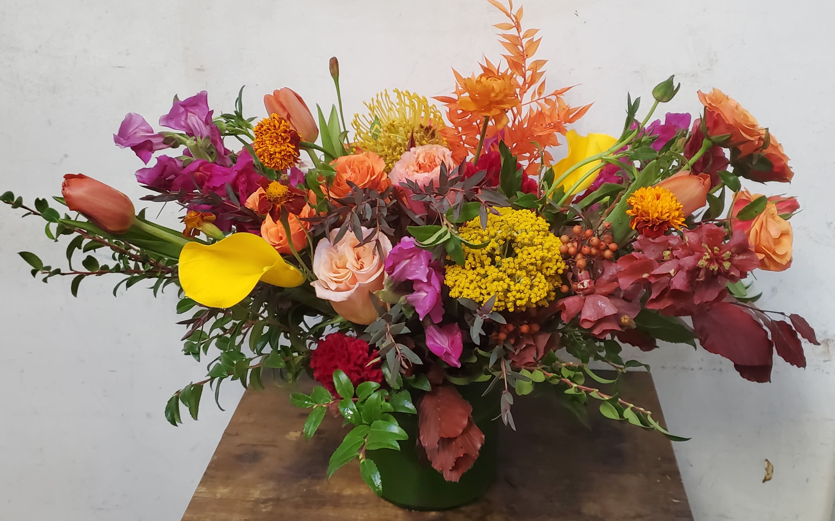 Mixed bouquet with roses, calla lilies, and bright orange and purple flowers in a vase