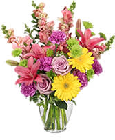 Mixed pink and yellow flowers in a clear glass vase