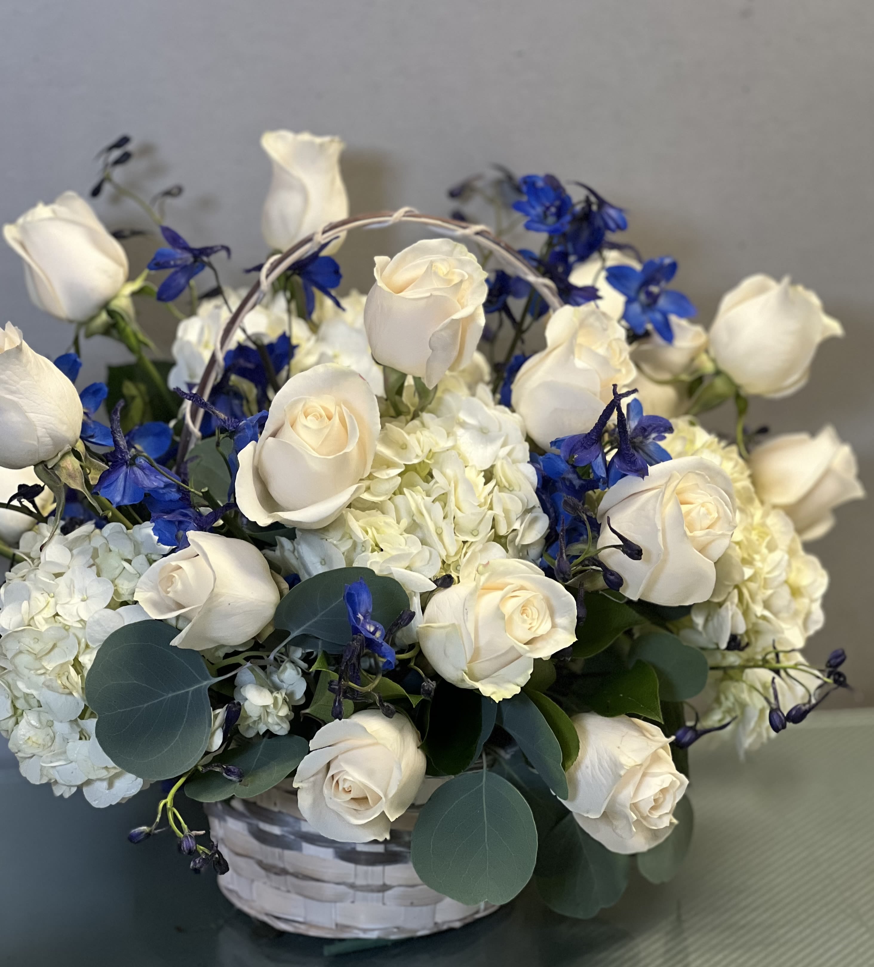 White roses and blue flowers in a white basket