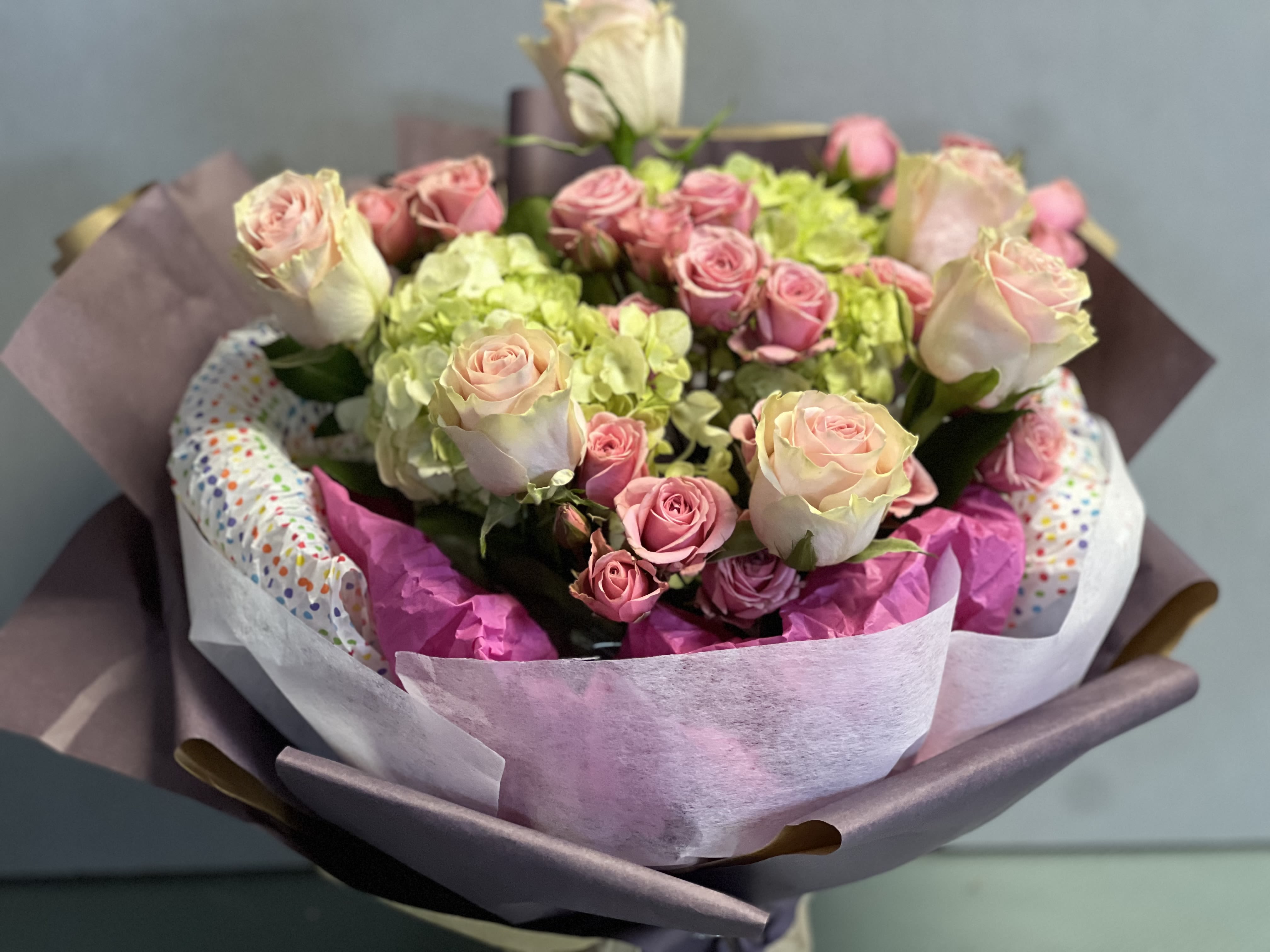 Bouquet of pink roses and green hydrangeas wrapped in pastel paper