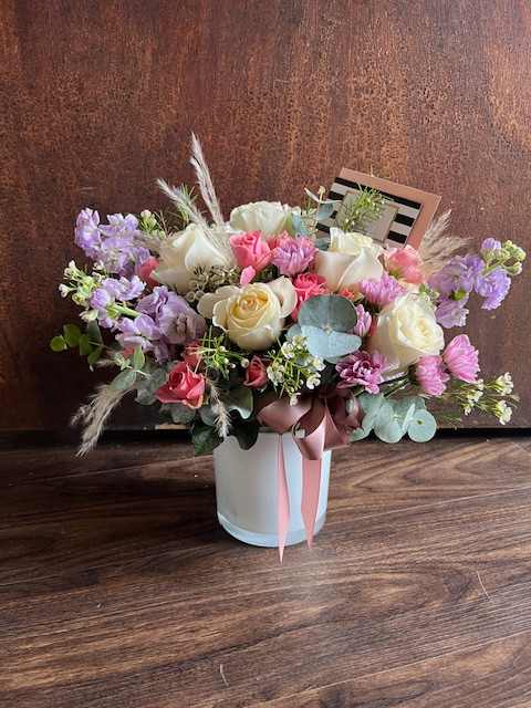 Mixed bouquet of pink, white, and lavender flowers in a white vase