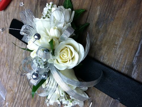 White rose corsage with silver ribbon and pearl accents on a black band