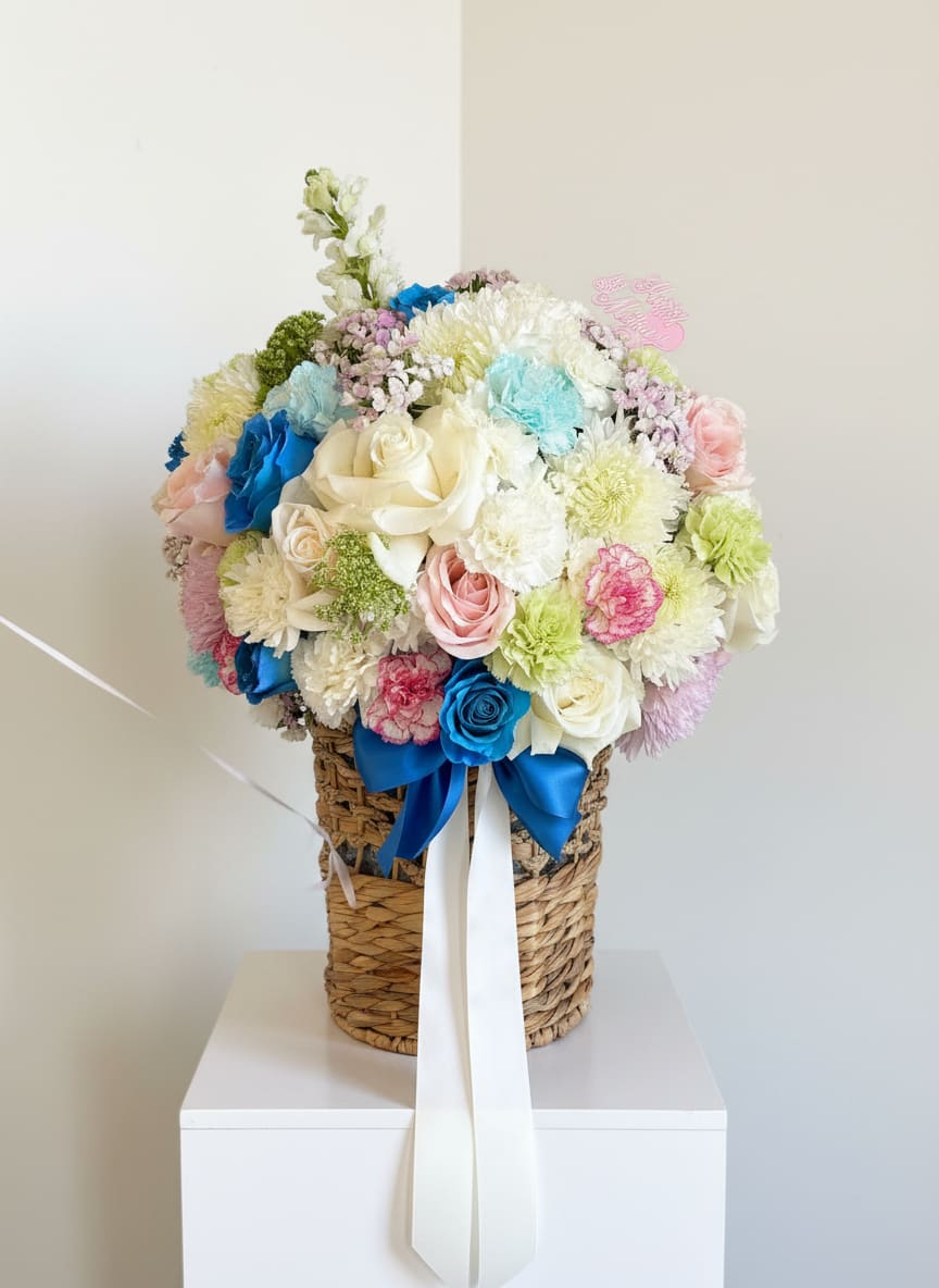 Baby Blue Basket - Soft white florals with vibrant blue accents arranged in a charming basket with satin ribbon