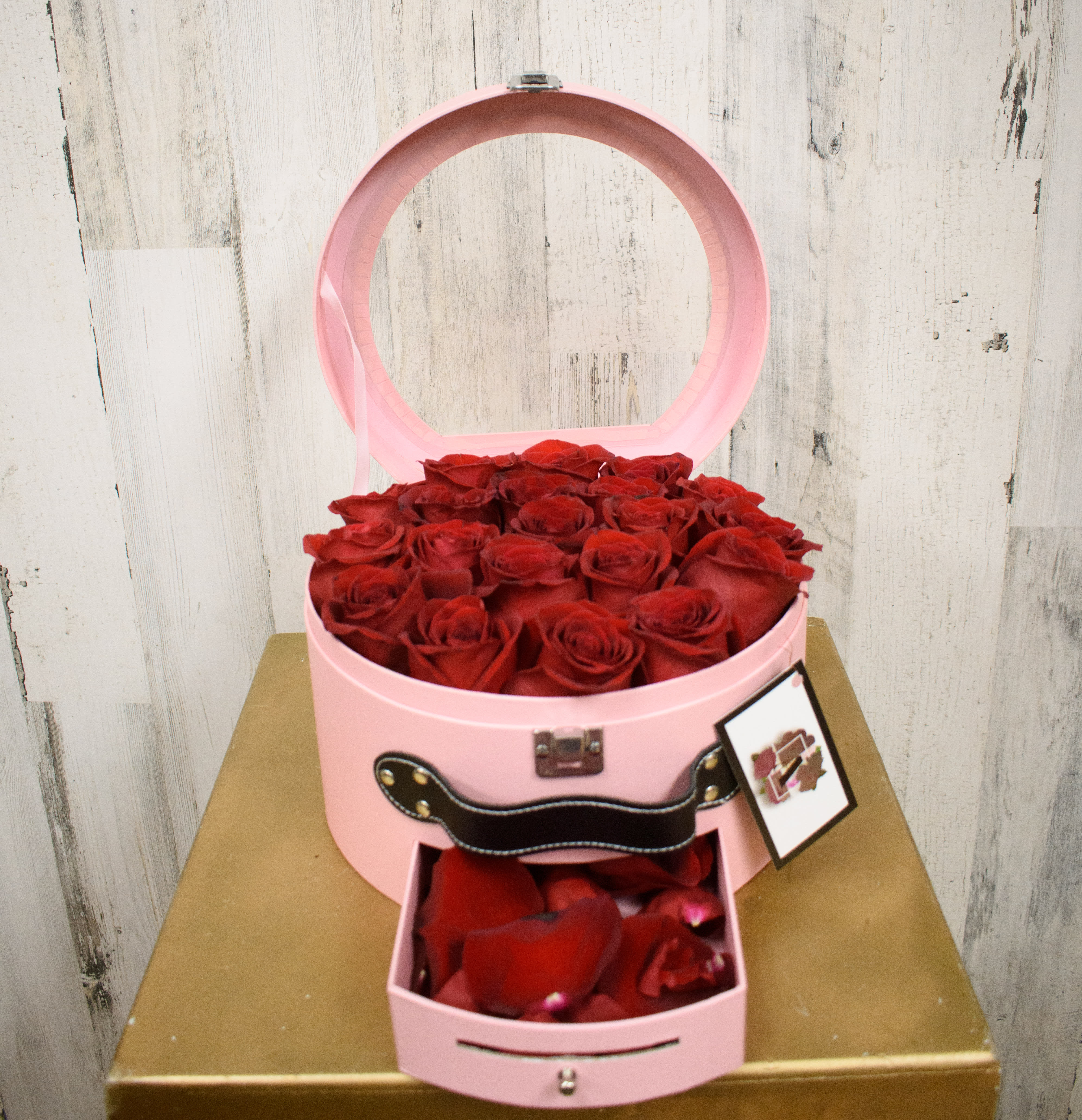 Come Fly with Me - Cute suitcase style box filled with premium red roses. Includes mini drawer at the bottom filled with rose petals. Perfect spot for a secret gift or gift card. Please specify in special instructions if you would like to change the rose color. 